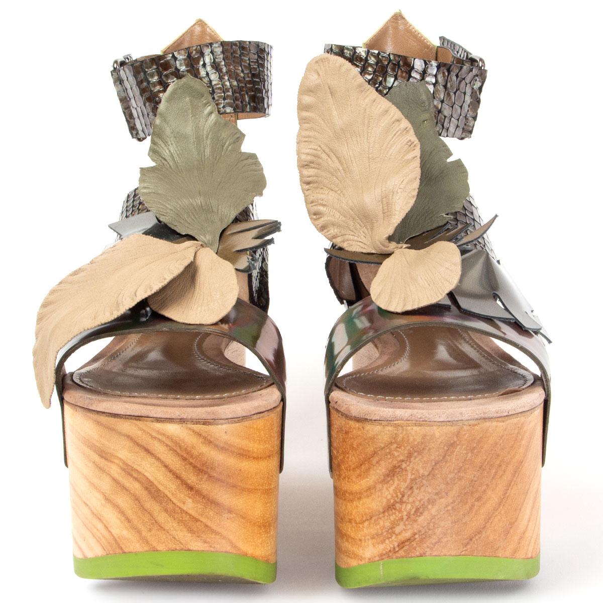 100% authentische John Galliano Plateausandalen aus Holz mit Knöchelriemen in Hellgrün, braunem geprägtem und holografischem braunem Lackleder, verziert mit taupefarbenen und olivgrünen Blättern. Sie wurden getragen und sind in einem ausgezeichneten