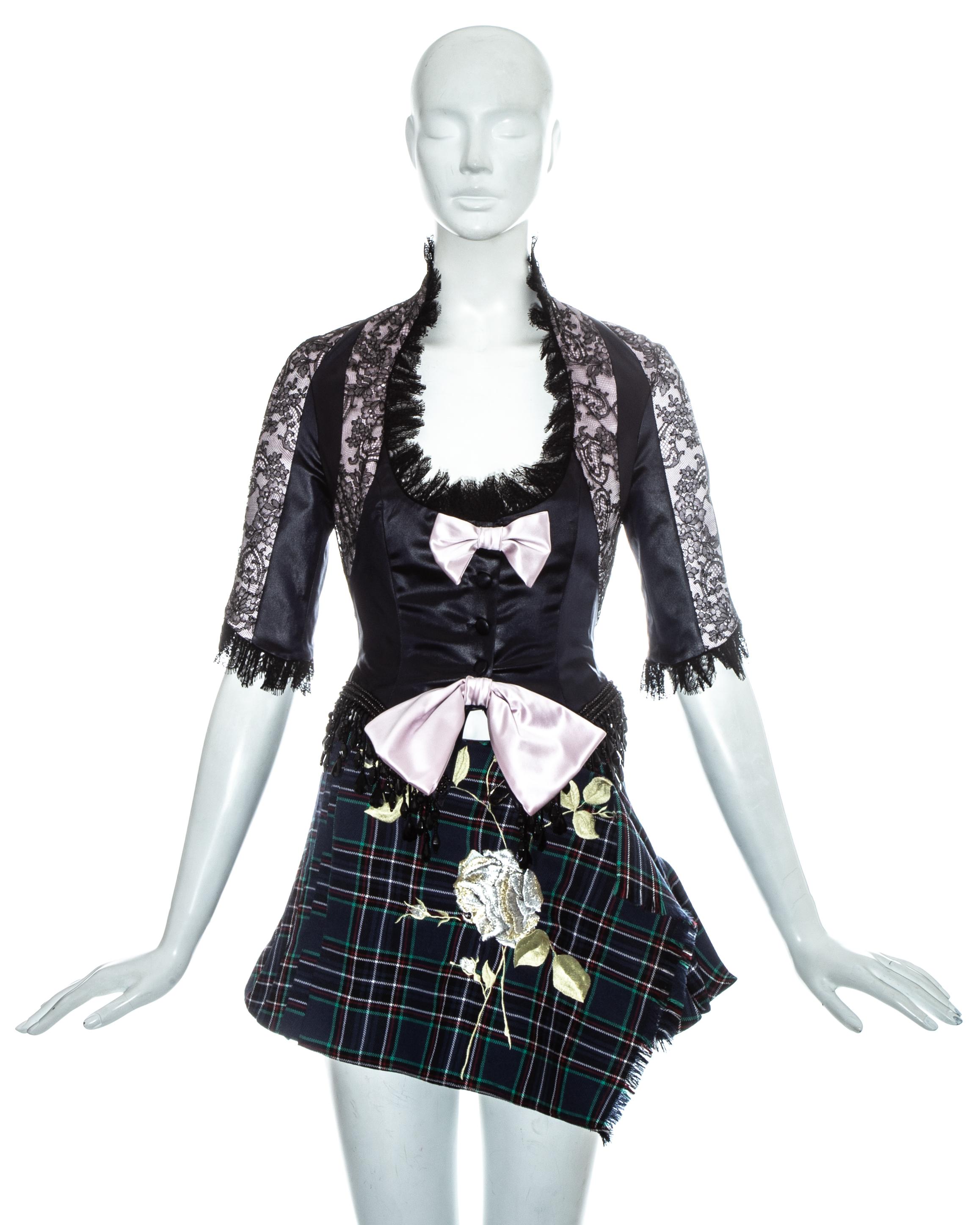 John Galliano runway ensemble. Pink lace and satin panelled corset with lace and beaded fringe trim, two decorative pink bows and fabric button fastenings.  Blue wool tartan micro mini wrap skirt with sewn pleats, large safety pink fastening and
