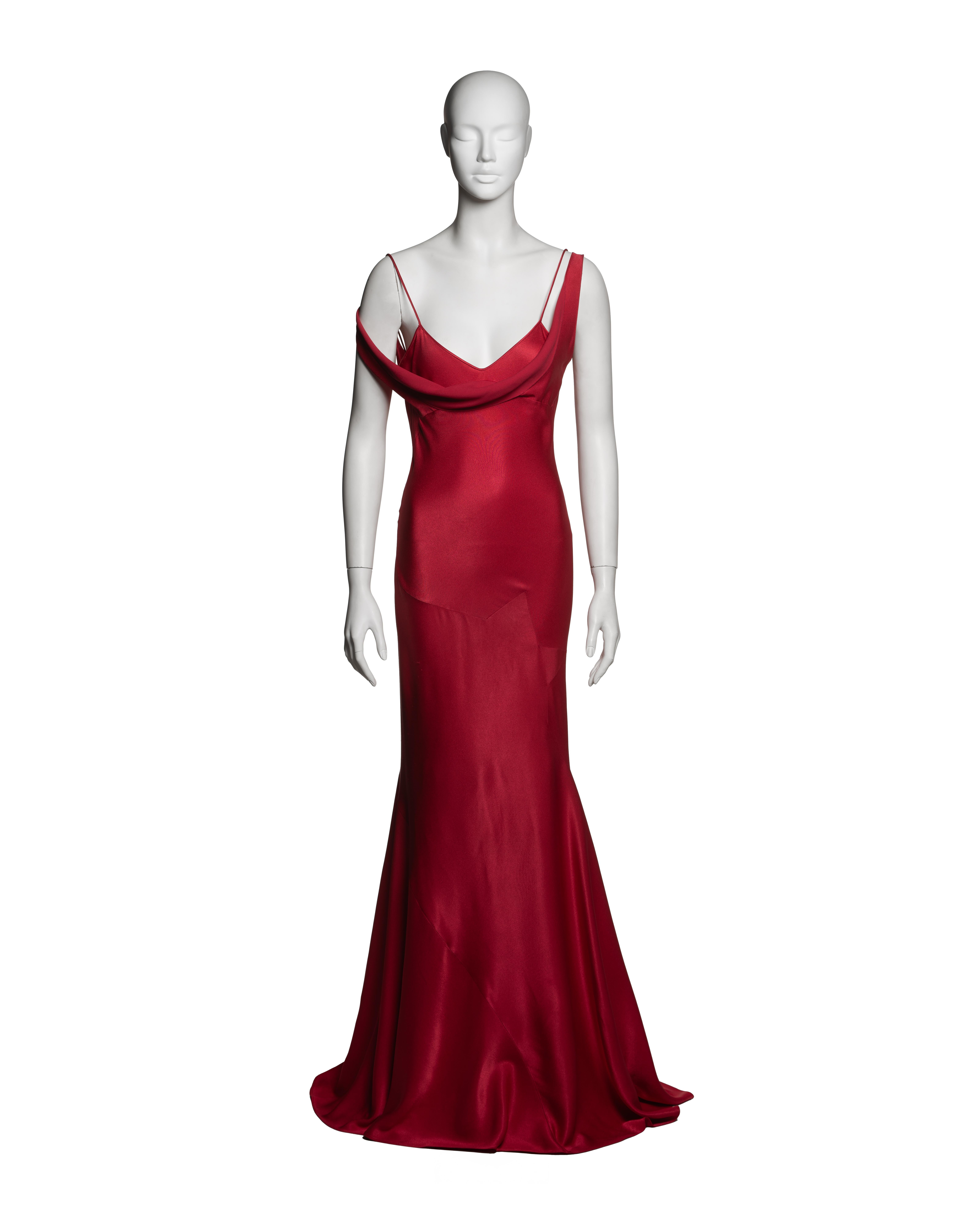This John Galliano evening dress from the Fall-Winter 1994 collection is crafted from bias-cut crepe-backed satin in a crimson hue. The gown features a softly draped cowl neckline, delicate double spaghetti straps—one intentionally shortened for a