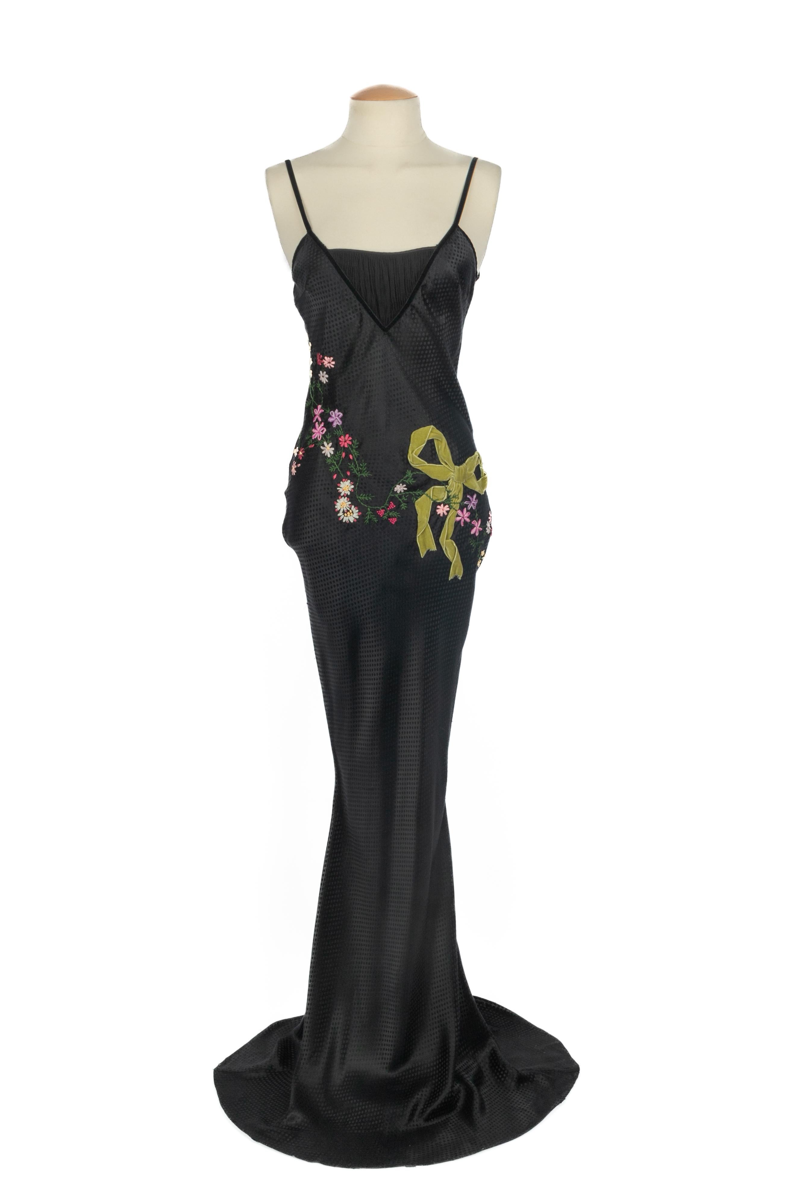 JOHN GALLIANO - Vestido de seda negra bordado con flores multicolores y decorado con un lazo de terciopelo verde. No se indica la talla, se ajusta a una 36FR.

Estado:
Muy buen estado

Dimensiones:
Pecho: 43 cm - Cintura: 35 cm - Caderas: 44 cm -
