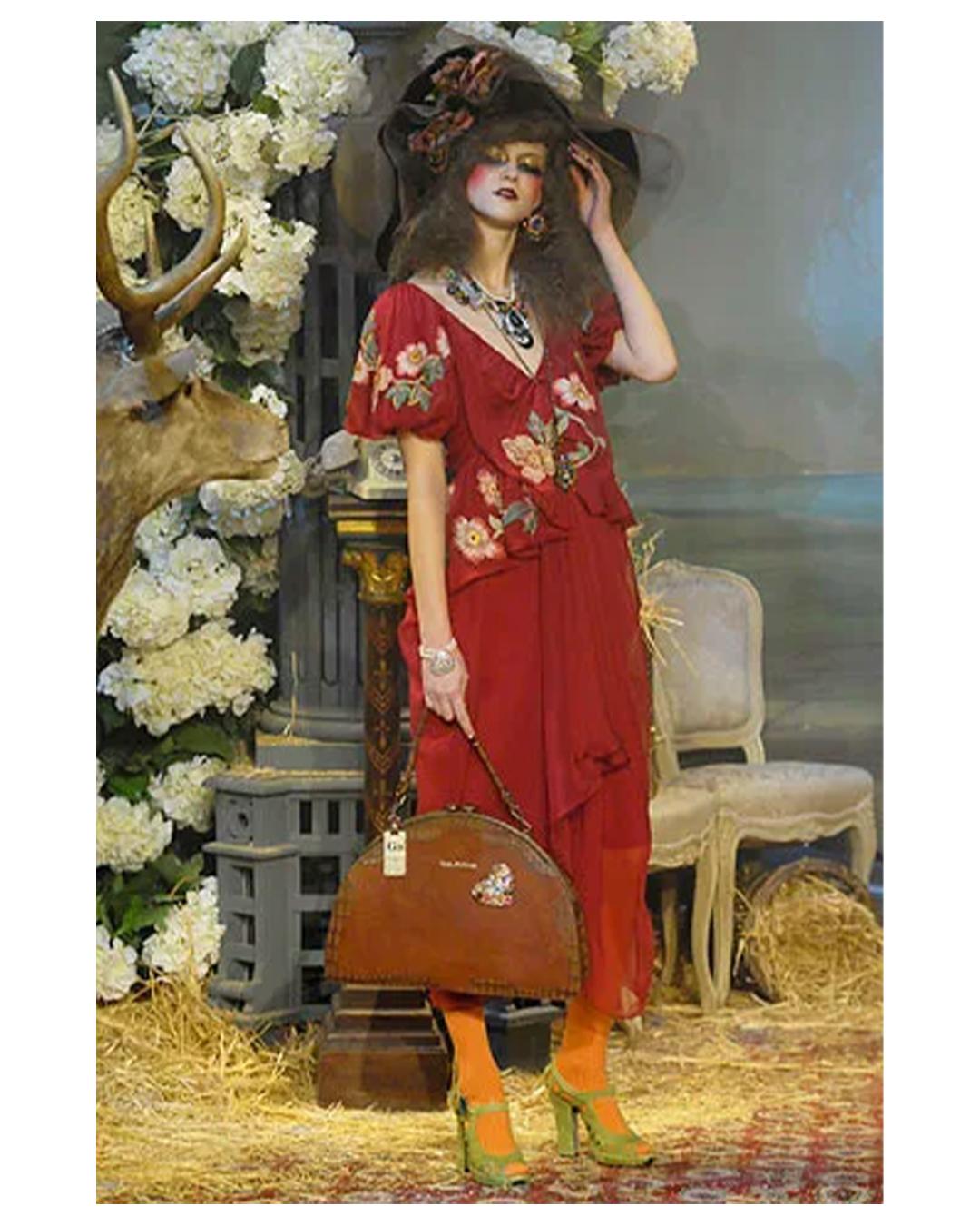LOVE LALI VINTAGE

John Galliano Fall 2007 Look 13 dress
Beautiful short sleeve dress in burgundy silk with brightly coloured floral appliqué and embroidery in an array of pink and greens
V neck line and back
Short puff sleeves
Sheer draped skirt
