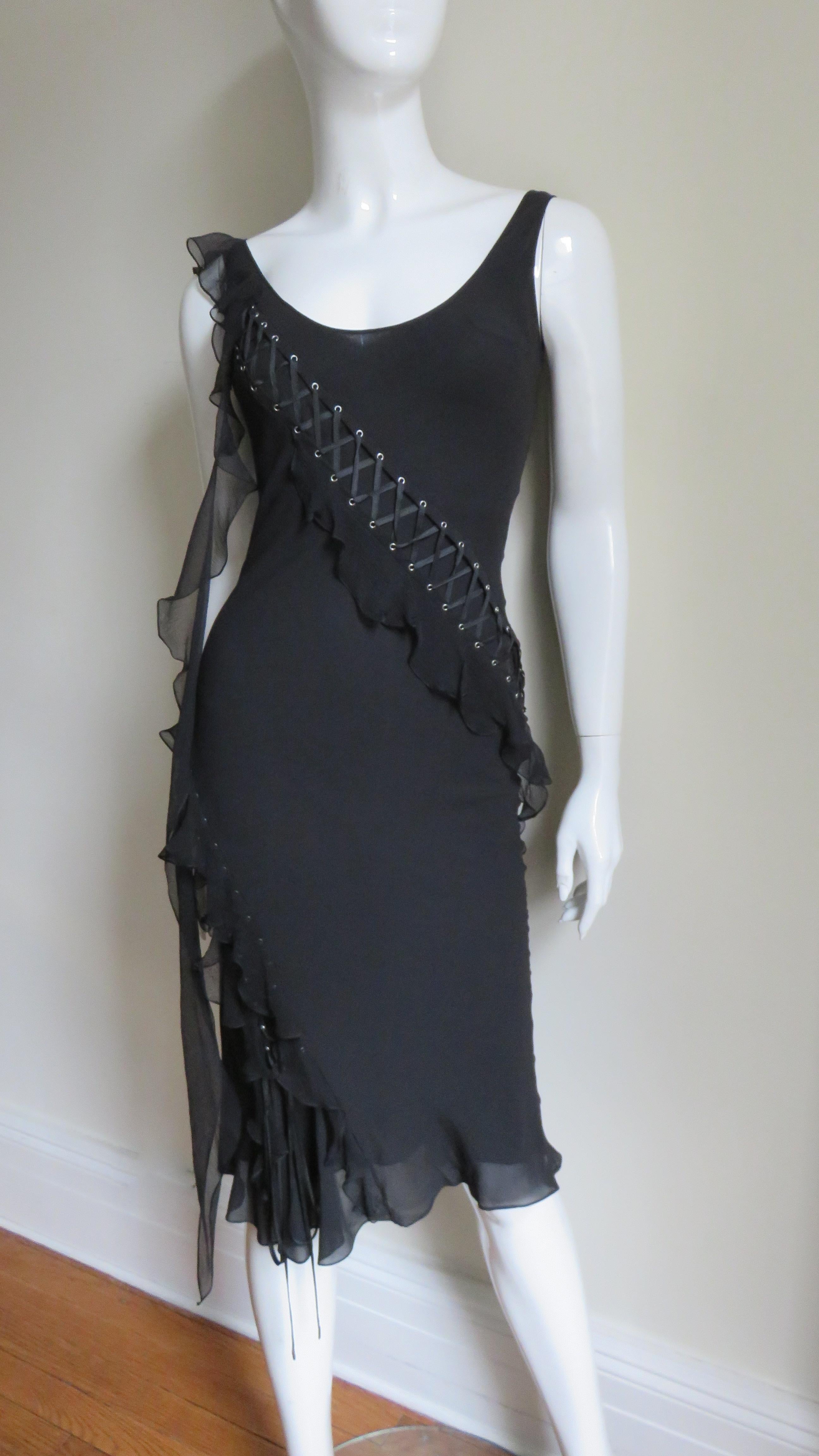 A fabulous black fine silk dress with stretch from Christian Dior.  It has a scoop neck front and back with intricate lacing starting at one shoulder crossing the front and back wrapping around the hips to the hem.  A sheer silk ruffle follows the