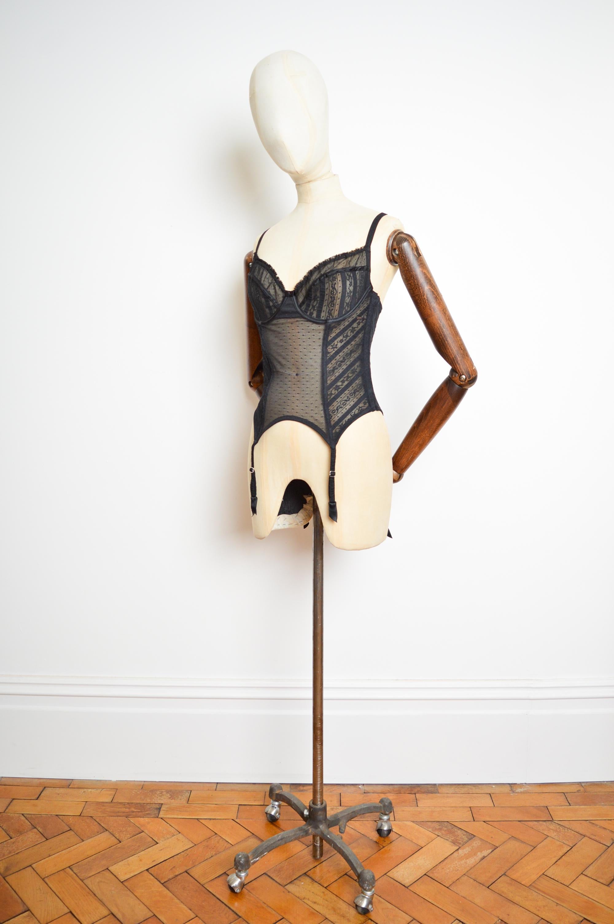 Erhabenes Korsett im Dessous-Stil aus schwarzer Spitze von John Galliano für Christian Dior. (CIRCA 2006)

Das Kleidungsstück ist aus dehnbarer, schwarzer, fein verzierter Spitze mit ergänzenden transparenten Einsätzen und Plissee-Rüschen an den