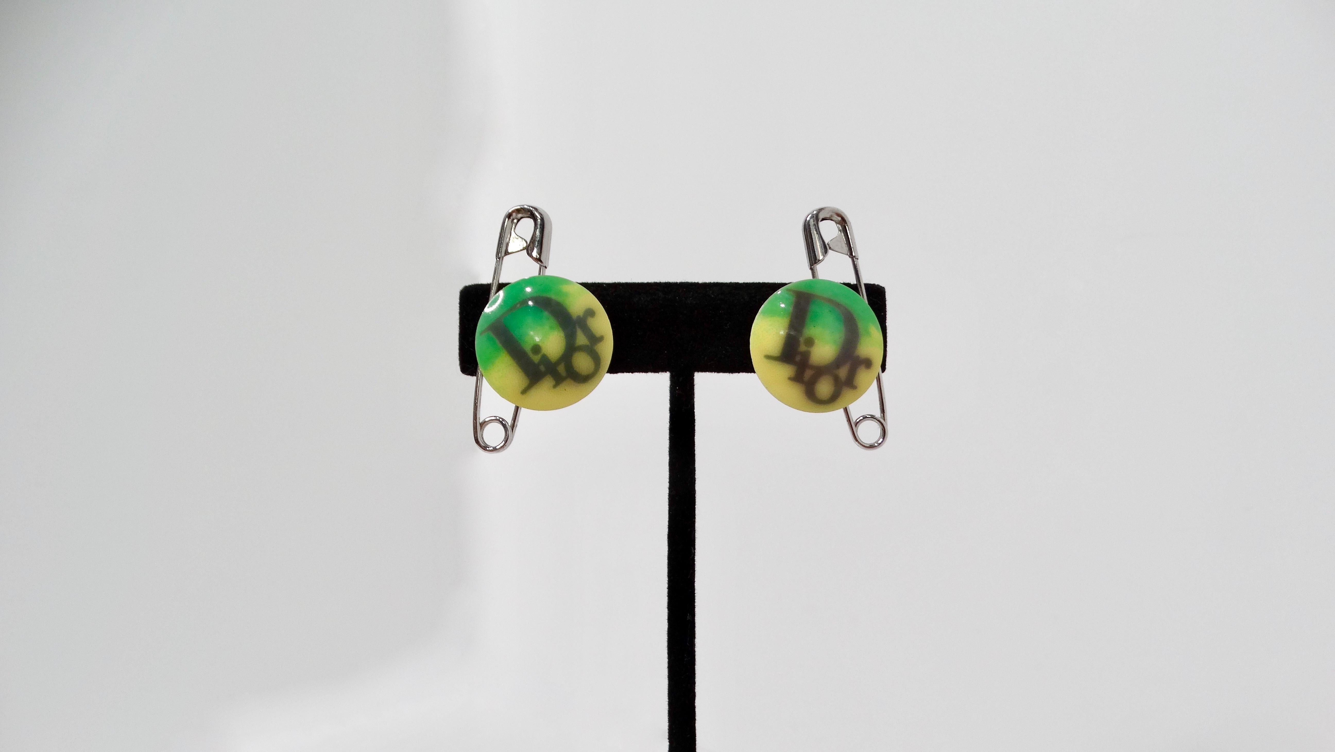 Step into a realm of nostalgia with the John Galliano for Christian Dior Y2K Logo Safety Pin Clip-On Earrings. These playful accessories feature vibrant green and yellow Dior logo pins artfully linked to silver-tone safety pins, encapsulating the