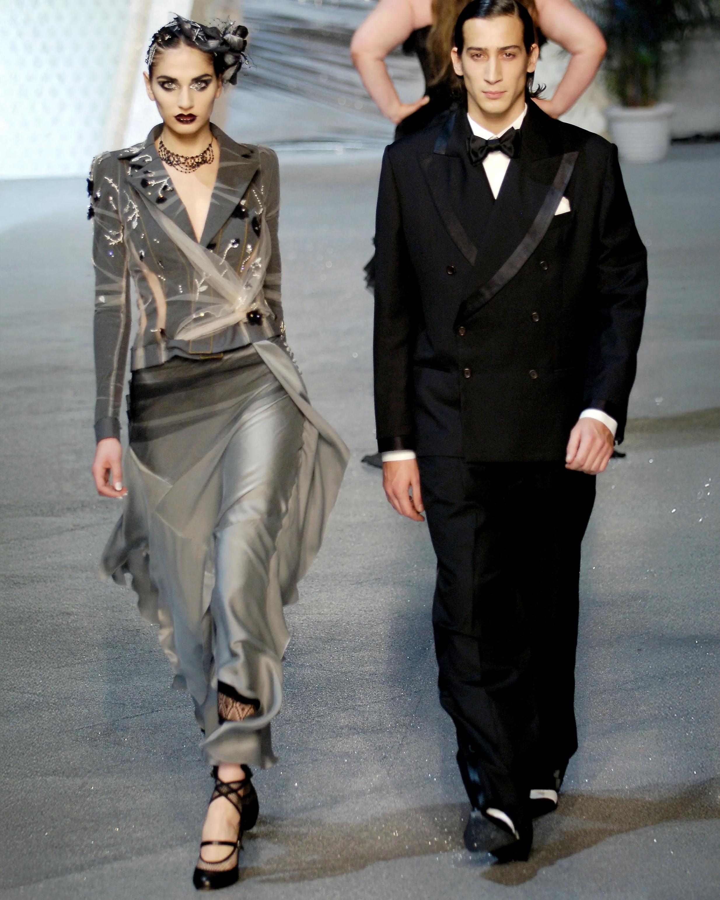 Gonna in seta di John Galliano della collezione Primavera-Estate 2006. Realizzata in un fluido raso di seta grigio, la gonna ha un taglio asimmetrico sul davanti, rifinito con pannelli a cascata in stile fazzoletto che si estendono in un orlo