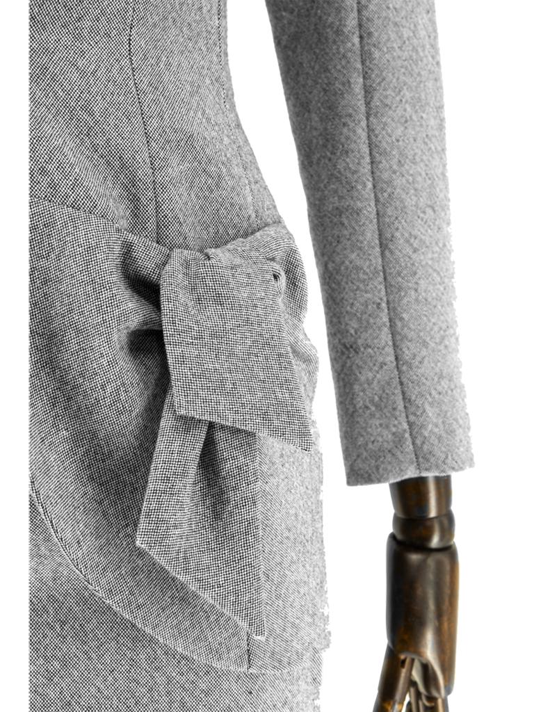 A late 1990’s John Galliano silver-grey fine wool plain weave suit, the elongated fitted panel jacket with complementing shawl collar and curved front hem, stylized grown-on raglan tapered sleeves and complementing knotted pigtail detail, fully