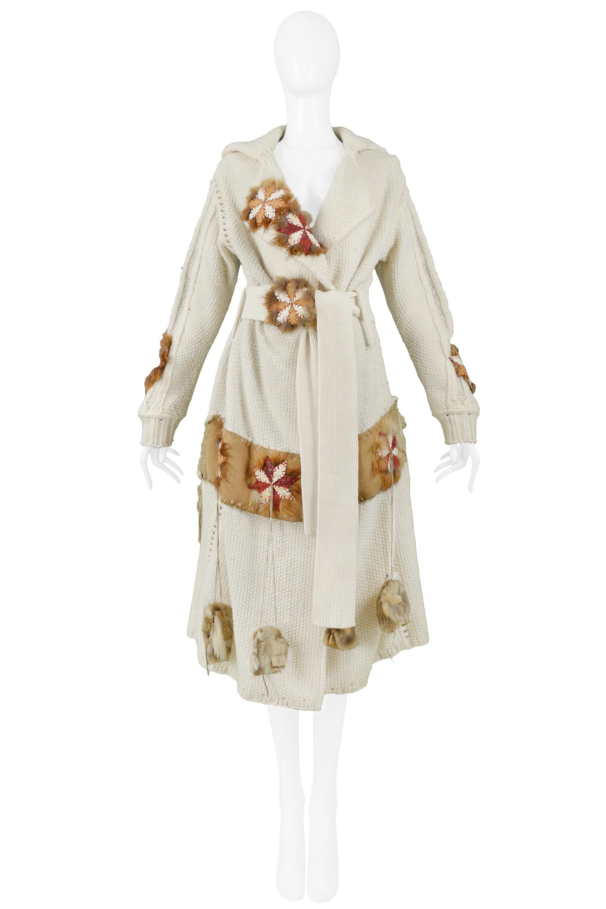 Resurrection Vintage is excited to offer a luxurious vintage John Galliano off-white long sweater coat featuring leather patchwork appliques that spell Galliano, leather trim, pinwheel appliques, red stitching, fur trim, and a matching belt. 

John