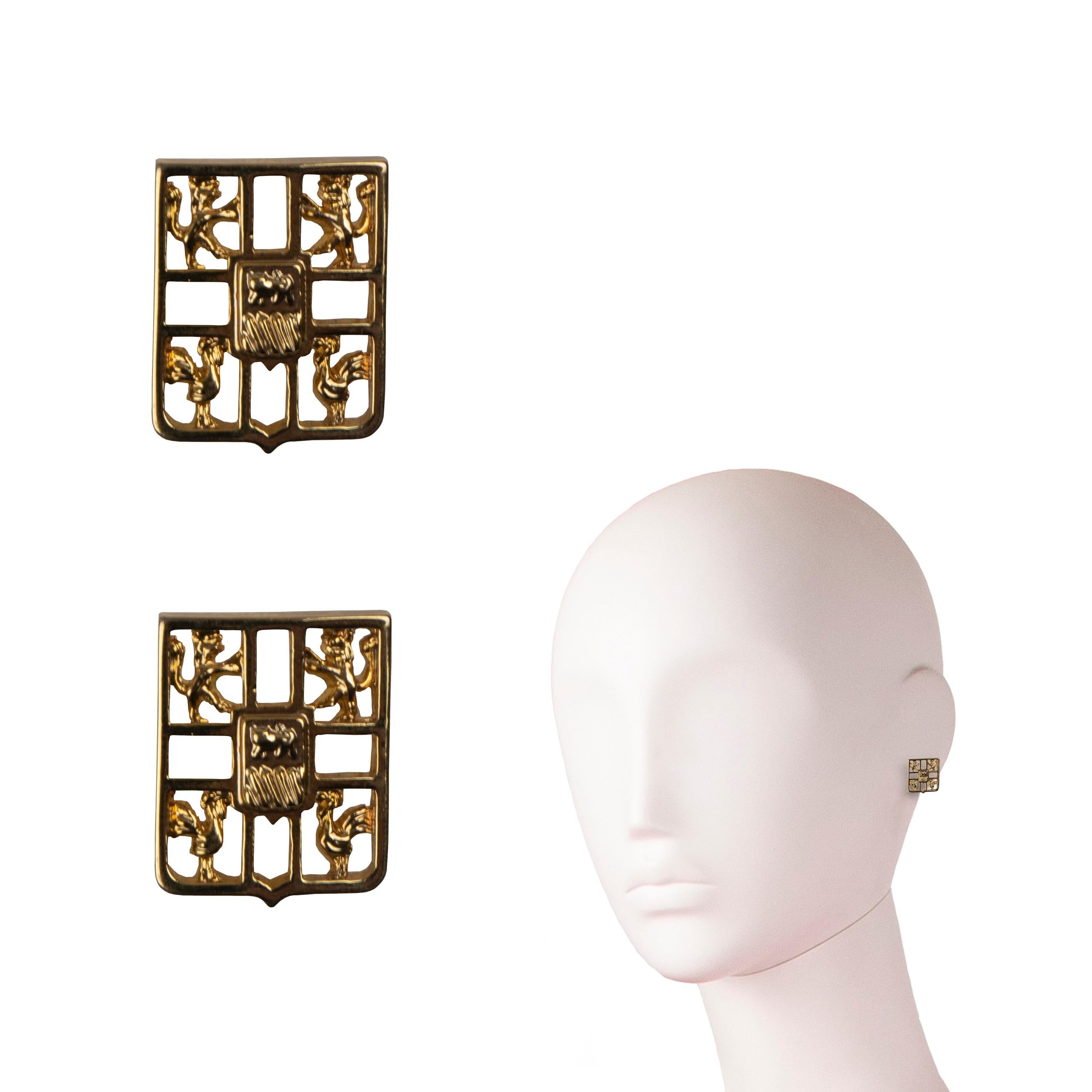 A pair of John Galliano logo earrings, circa 1996. These earrings showcase Galliano’s first logo, which was adopted from his family crest and debuted in the mid-80s. The logo, which appeared on garments until the early 2000s, is a hallmark of