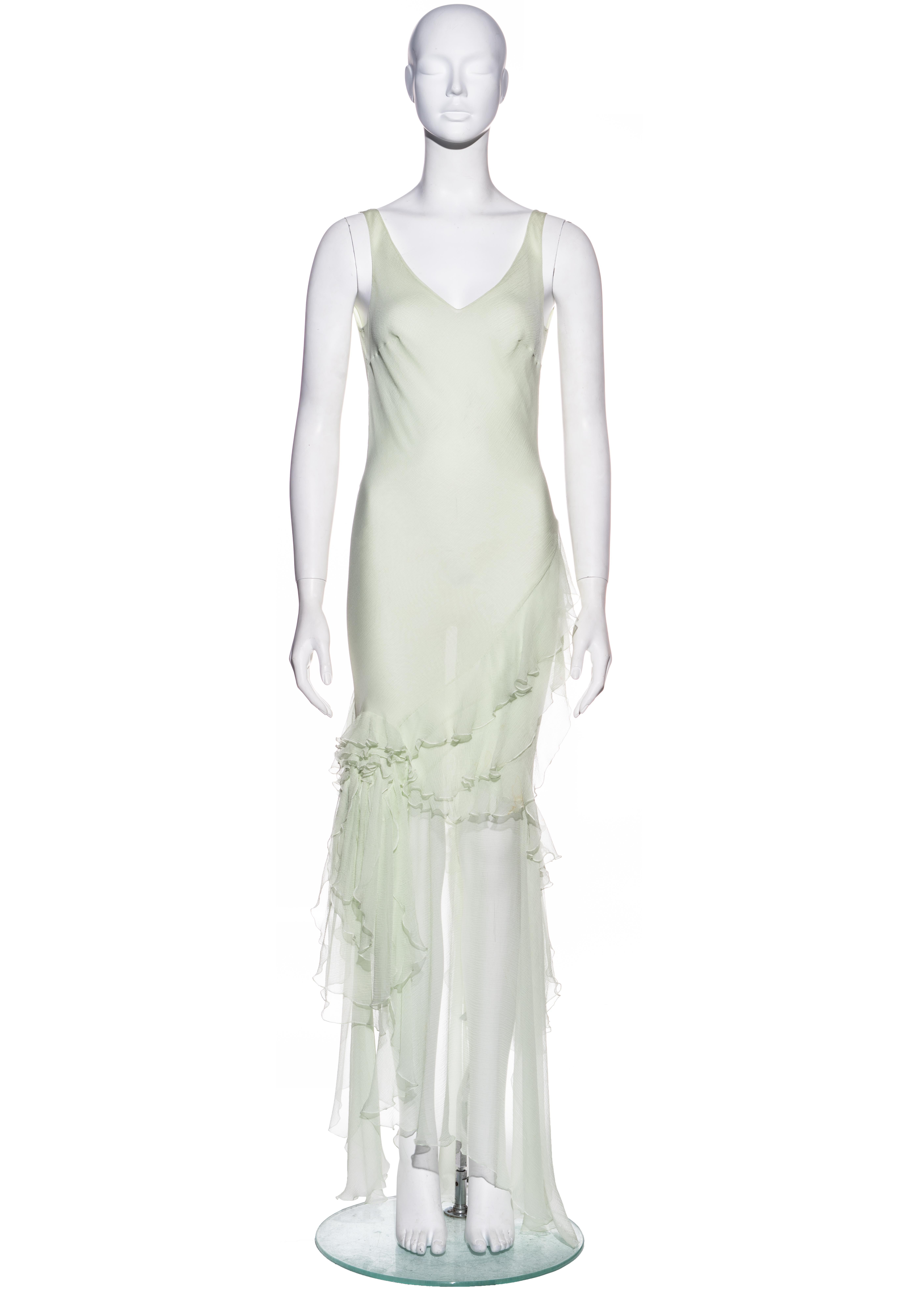 ▪ John Galliano pale green silk chiffon evening dress
▪ Bias cut 
▪ Silver chains and medallion pendant at back 
▪ Flounces encircling the skirt 
▪ Open back
▪ FR 40 - UK 12 - US 8
▪ Fall-Winter 1995
