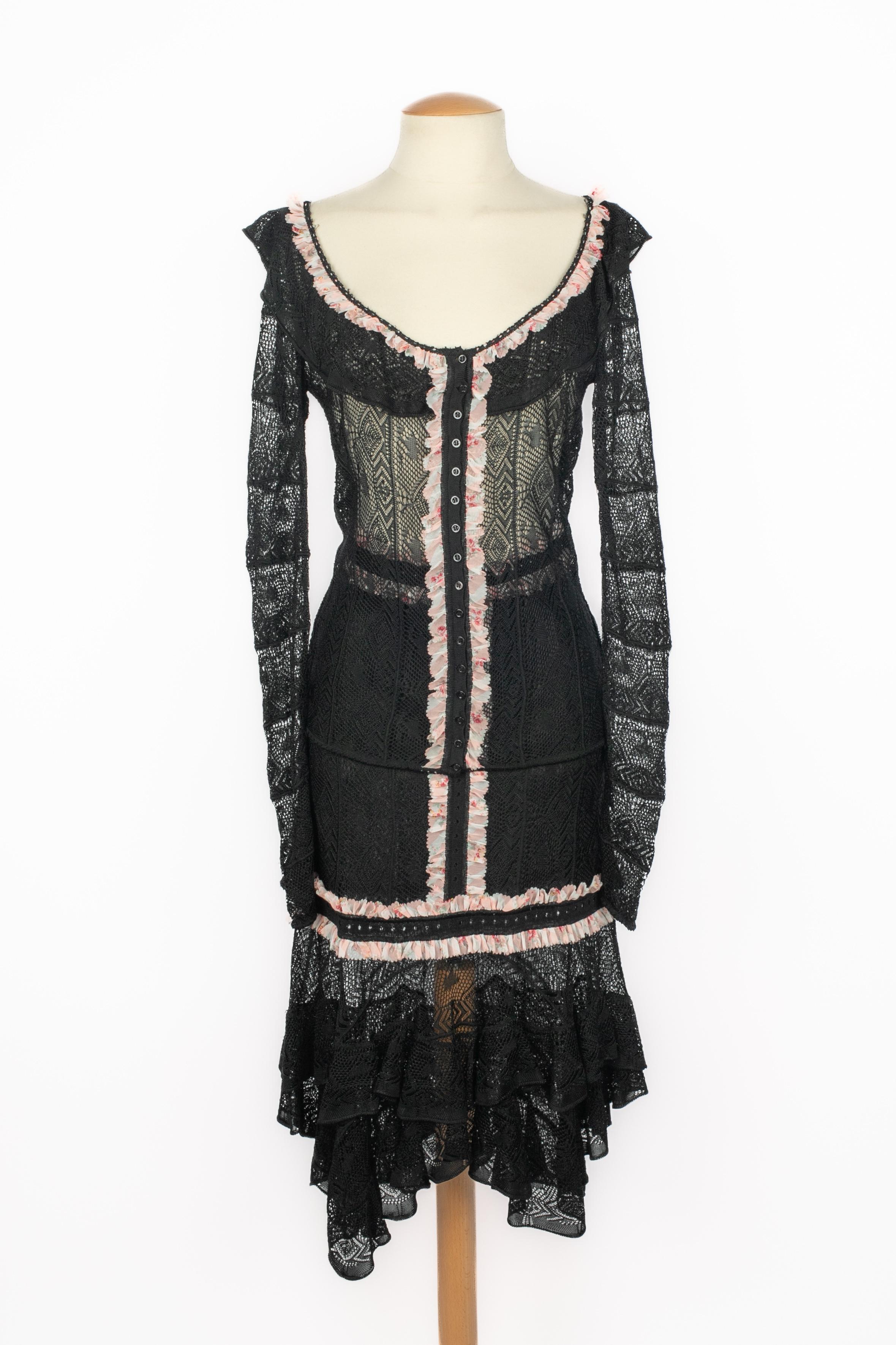 GALLIANO - (Made in Italy) Ensemble en maille ajourée noire composé d'une jupe et d'un top cardigan à manches longues, bordé d'un volant à motifs de fleurs dans les tons roses. Taille M indiquée. Collectional printemps-été 2004.

Condit :
Très bon
