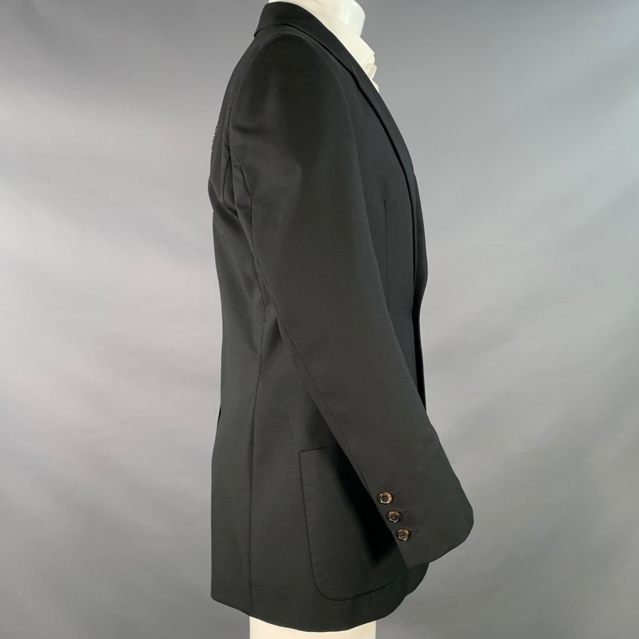 JOHN GALLIANO sport coat
in a black virgin wool featuring a back rhinestone studded skull design, notch lapel, single vented back, and double button closure. Made in Italy.Very Good Pre-Owned Condition. Brand tag removed. Minor mark on lapel