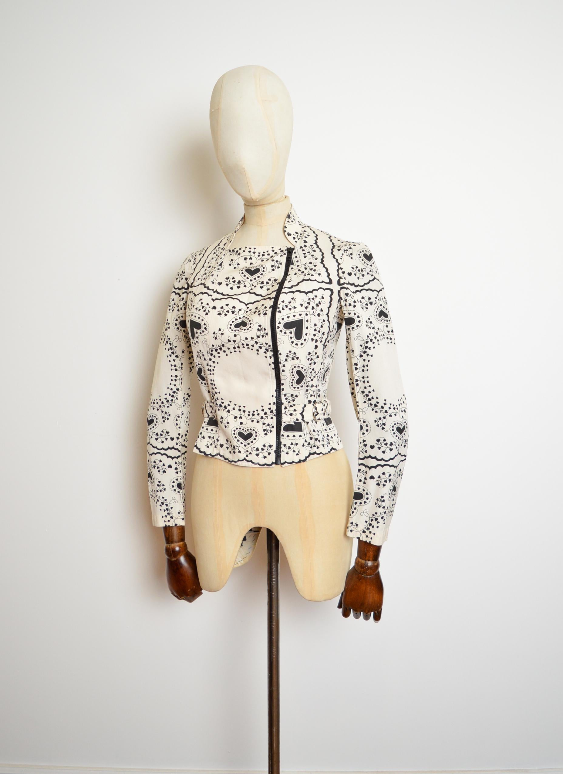 John Galliano Frühjahr 2002 Moto-Jacke aus einer Baumwoll-Seiden-Mischung mit schwarzem und ecrufarbenem Herz-Print.

Diese entzückende Jacke ist wunderschön geschnitten, hat verstellbare Seitengürtel, einen asymmetrischen Reißverschluss und einen