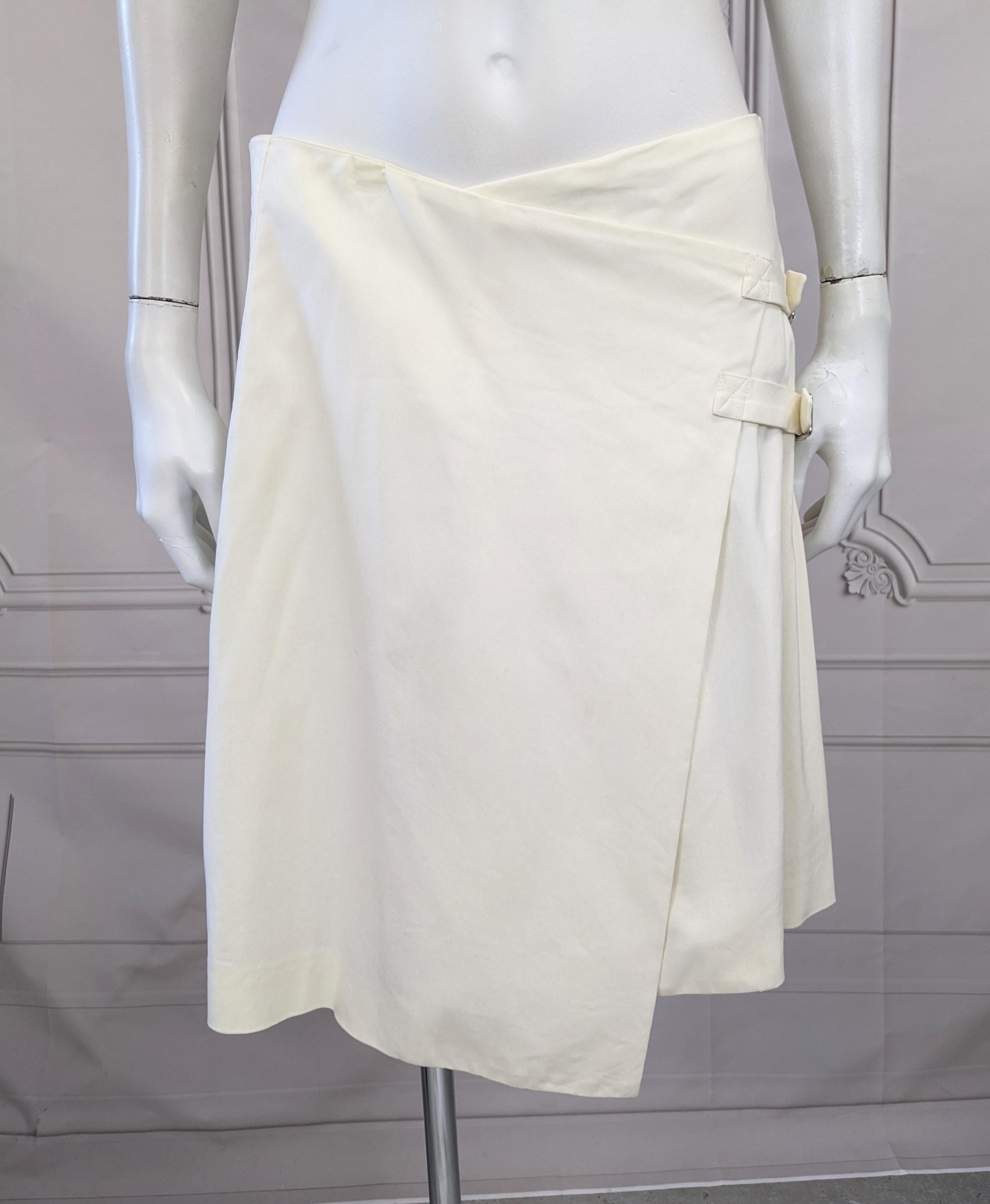 Interesting John Galliano asymmetrical deconstructed white polished rayon stretch twill wrap skirt from Spring/Summer 2000. The wrap style sits on the hips with two self buckle straps which morphs into a box pleated kilt. Excellent Condition, USA 6.