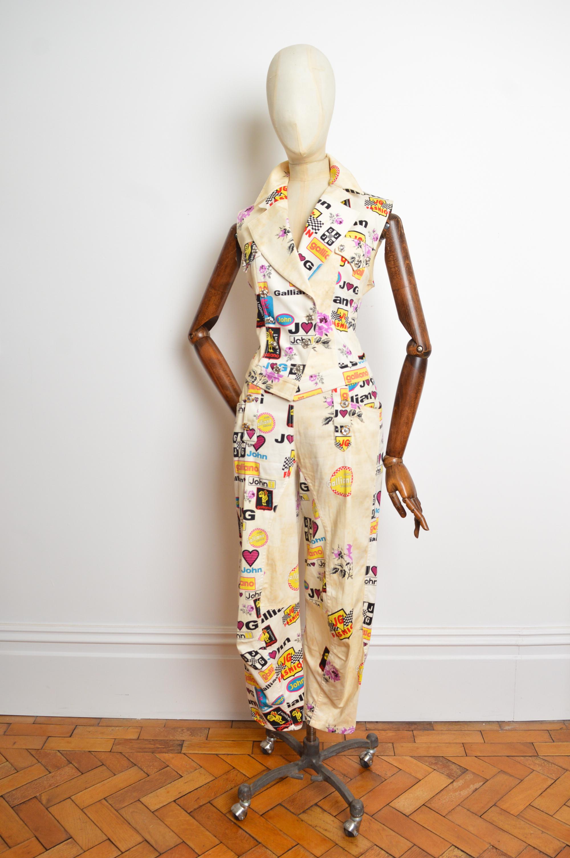 A fabulous John Galliano Spring /Summer 2002 Runway Ensemble, comprising a fitted double breasted Waistcoat Top & Matching Low rise ‘Harem’ style Pants.
This superb print is ornately decorated with ‘John Galliano fashion’ Slogans and tea-stained