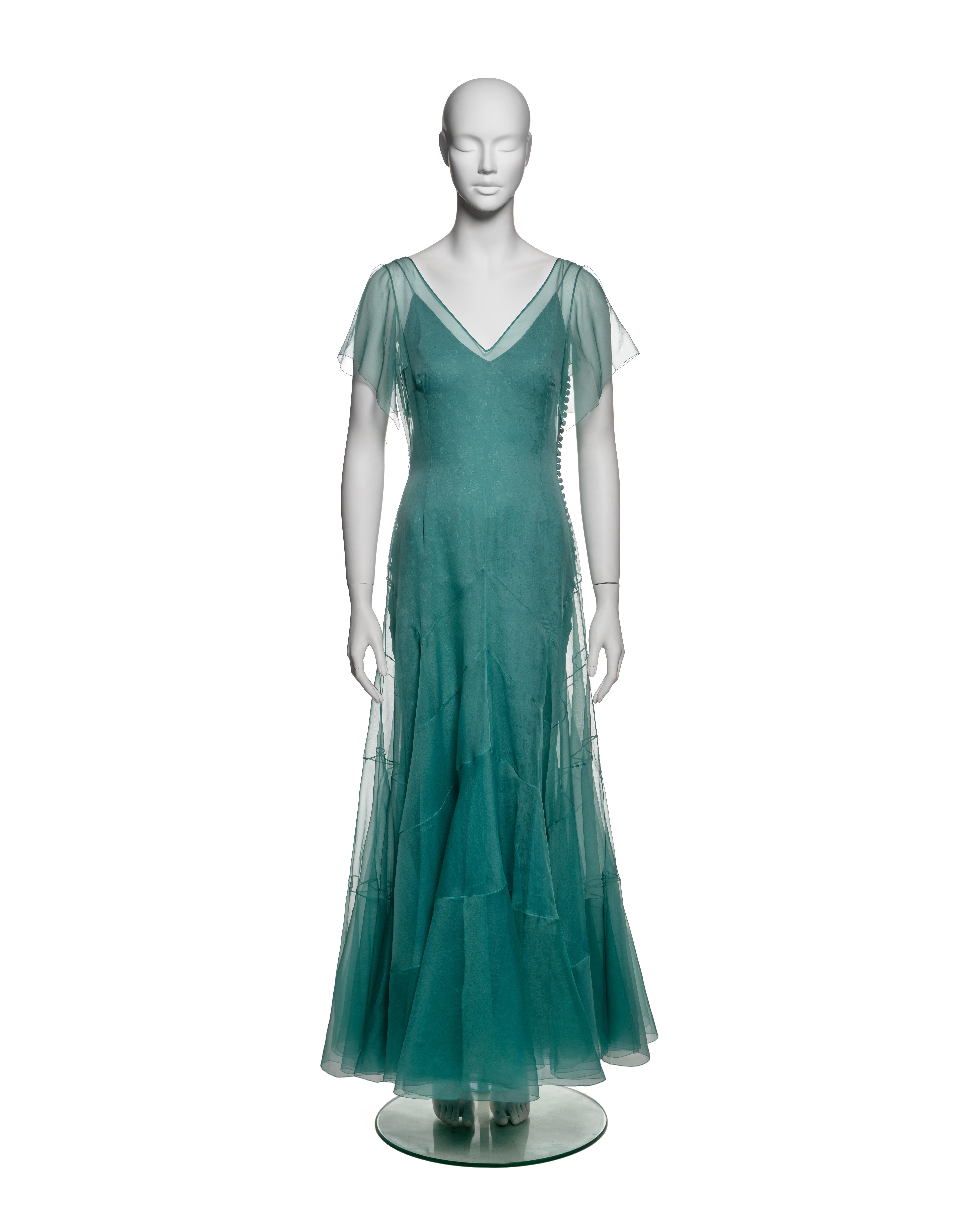 This John Galliano dress from the Spring-Summer 1998 collection features a single layer of teal silk organza, constructed with intricate paneling that gives the skirt a structural, fluid shape. The dress has a deep V-neckline and soft flutter