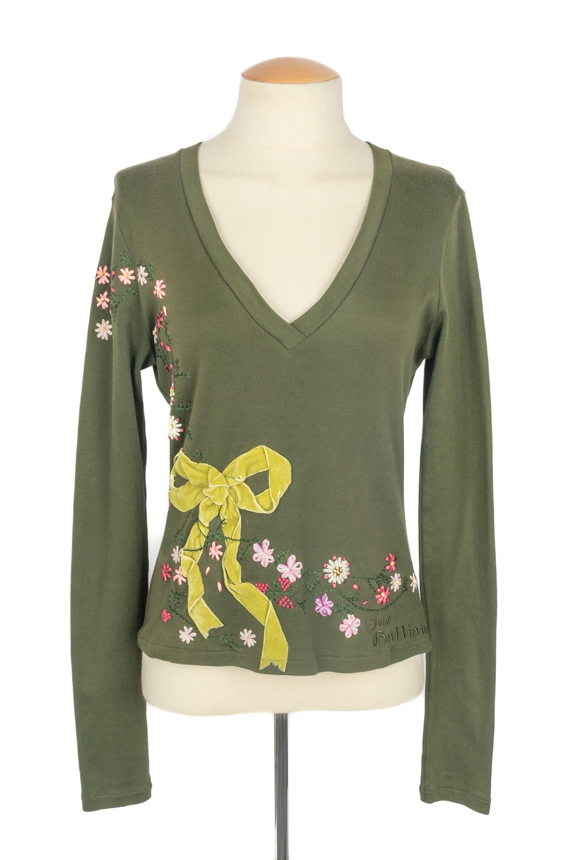 GALLIANO - Top verde de manga larga bordado con un motivo floral y decorado con un lazo de terciopelo verde. No se indica la talla, se ajusta a una 36FR/38FR.

Estado:
Muy buen estado

Dimensiones:
Anchura de los hombros: 44 cm - Pecho: 45 cm -
