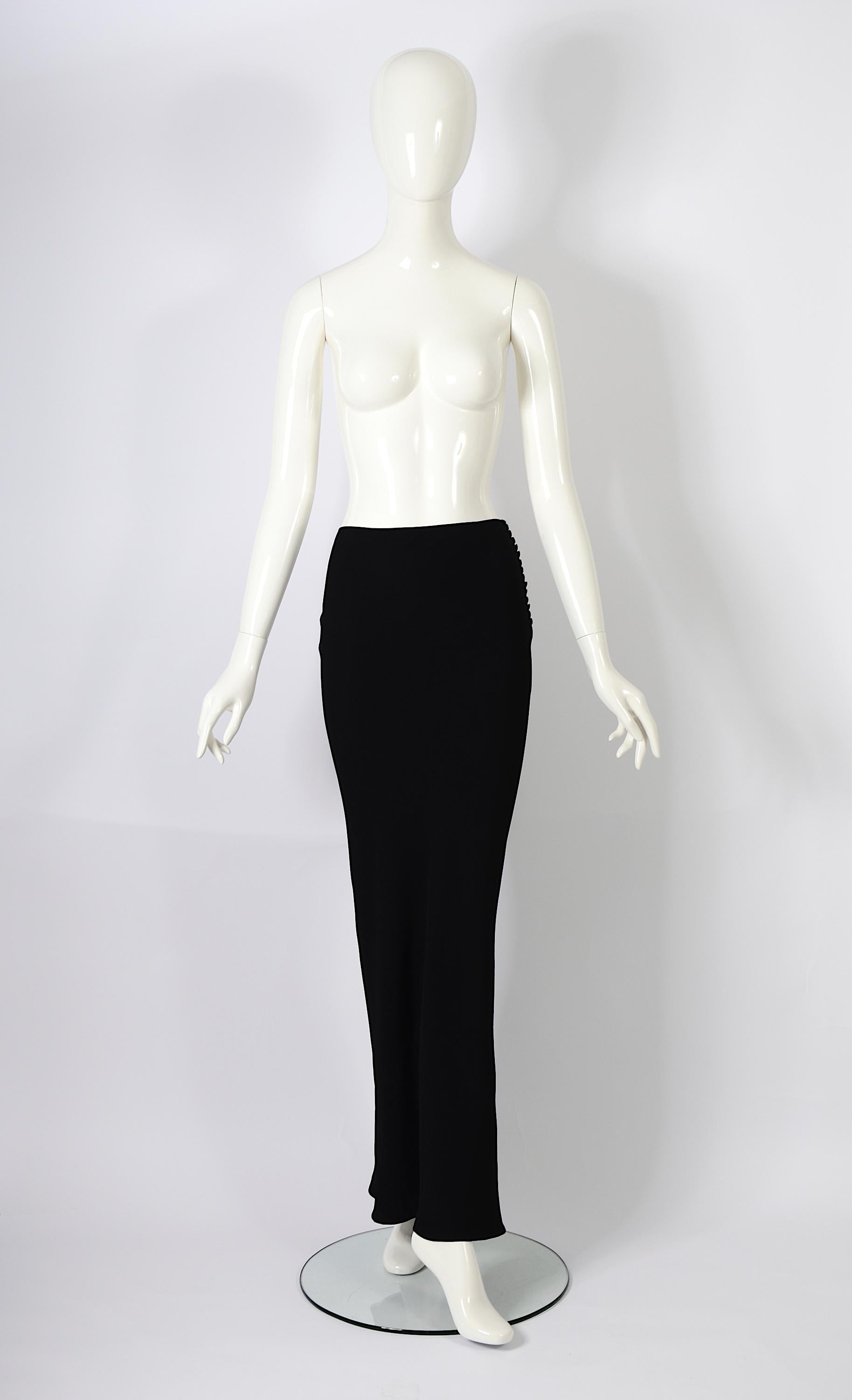 Cette magnifique jupe longue noire vintage des années 1990 en viscose soyeuse de John Galliano est coupée dans le biais pour une coupe flatteuse. Son design crée un charmant effet sirène dans le dos, tandis que les boutons soyeux assortis sur le