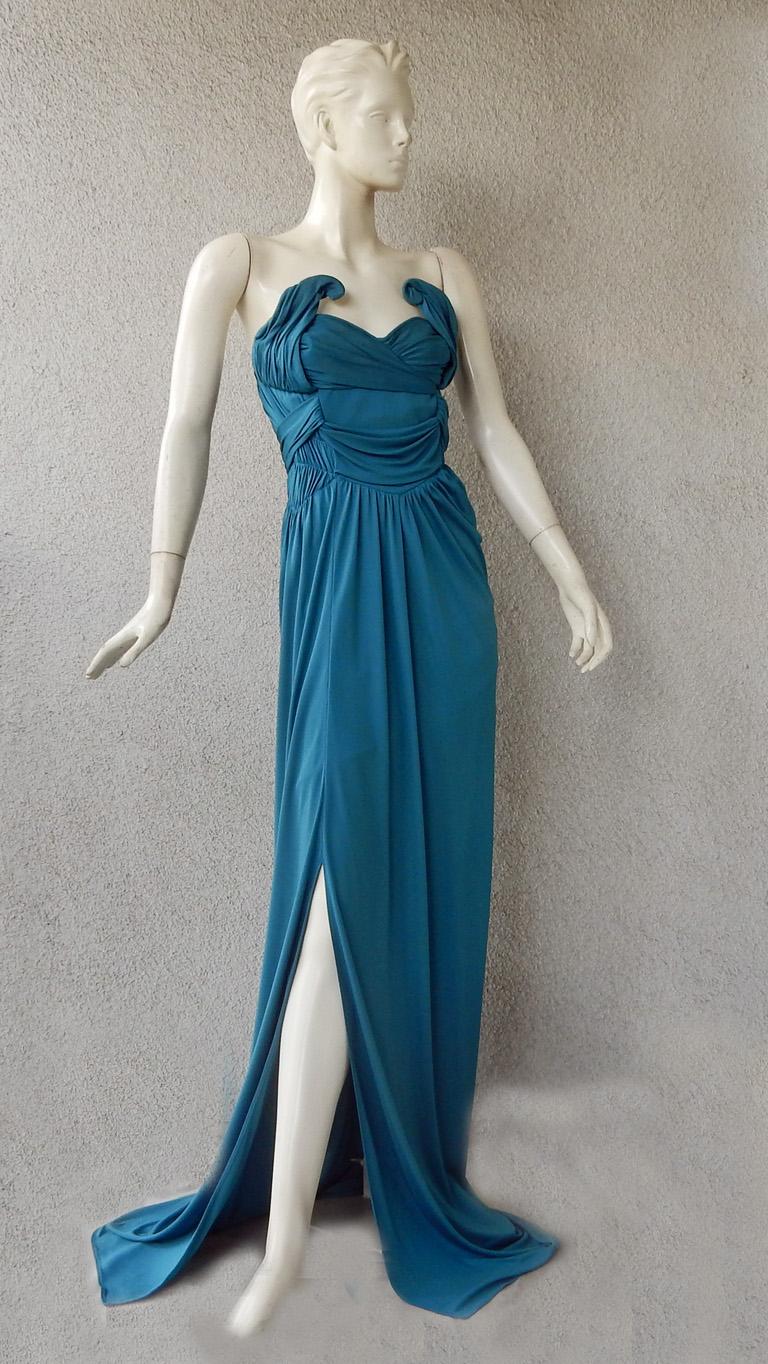 John Galliano 2009 Grecian inspired gown.  Fashioned in a rich teal blue fabric designed to delicately drape and showcase the body.  Lower back makes a dramatic fashion statement as it hangs and curves on the body. There is  tucking, and pleating