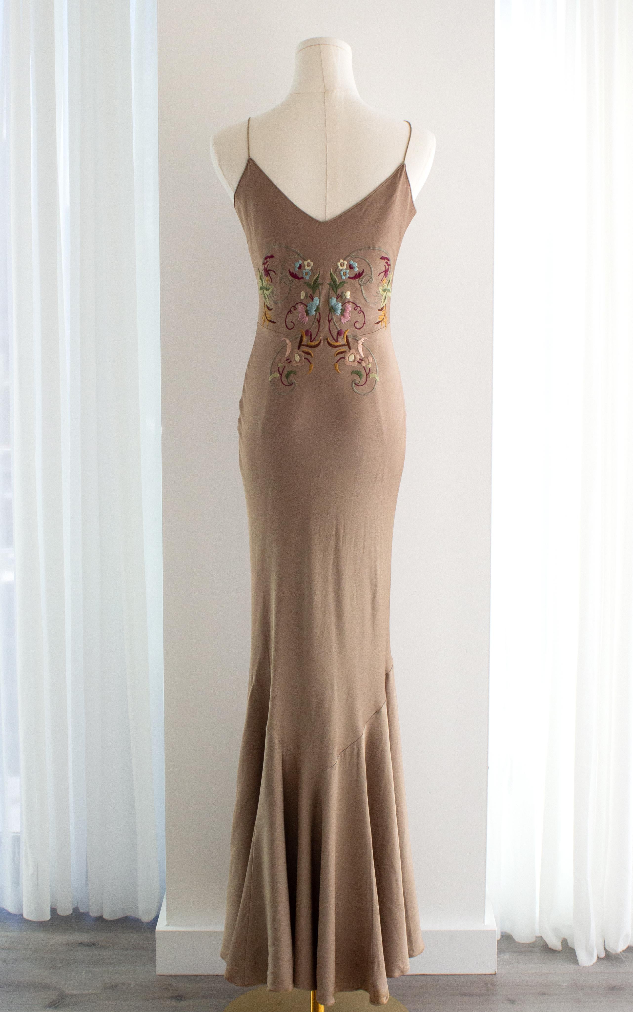 Questo squisito abito vintage di John Galliano della P/E 2003 è un pezzo sofisticato e senza tempo, caratterizzato da una ricca tonalità taupe-beige che emana eleganza. Disegnato con una sensuale silhouette a sottoveste, vanta delicate spalline,