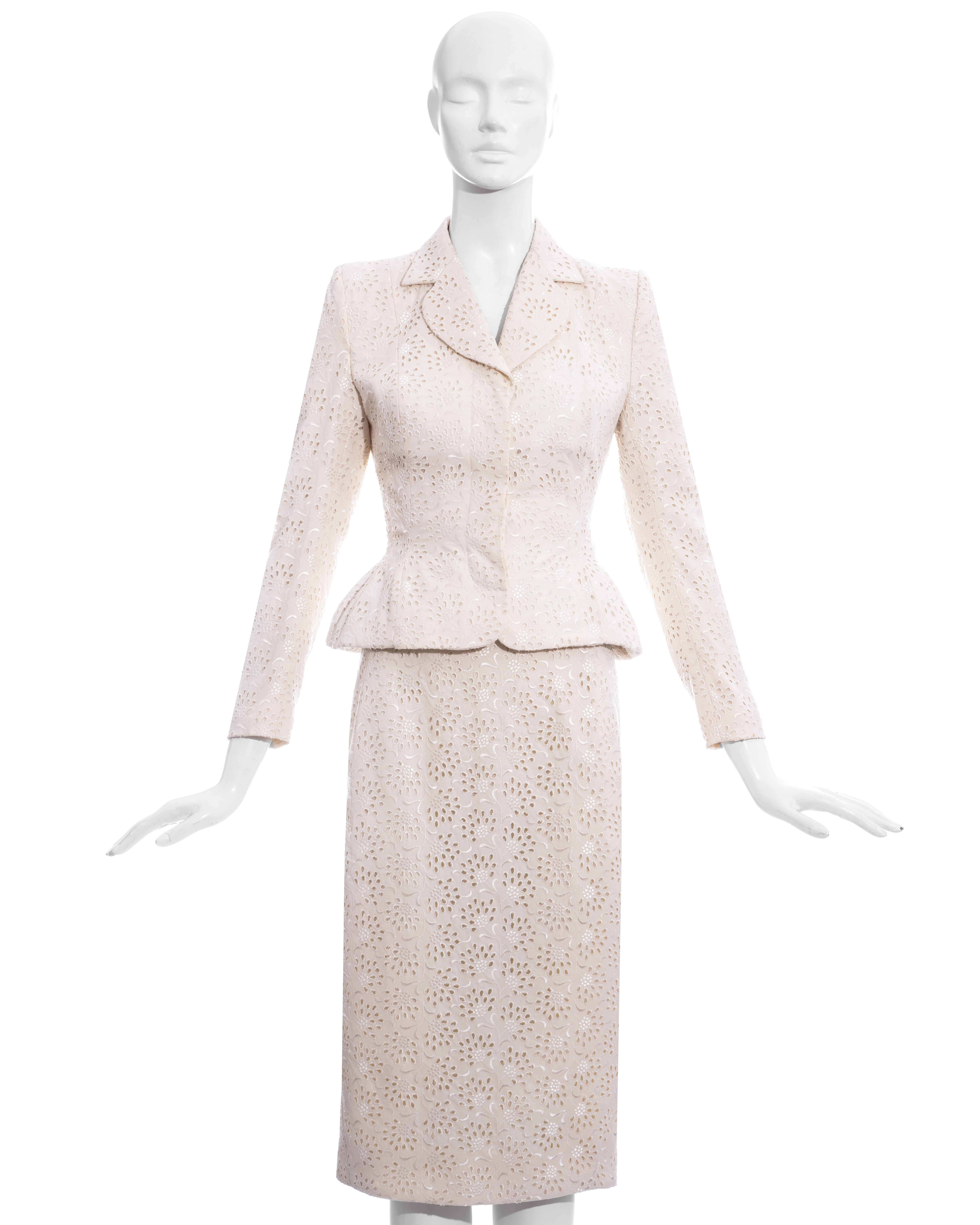 John Galliano white broderie anglaise cotton skirt suit comprising: fitted blazer jacket with hidden front button fastenings, notched lapel and accentuated waist and hips. Matching mid-length pencil skirt with back vent and zip fastening.