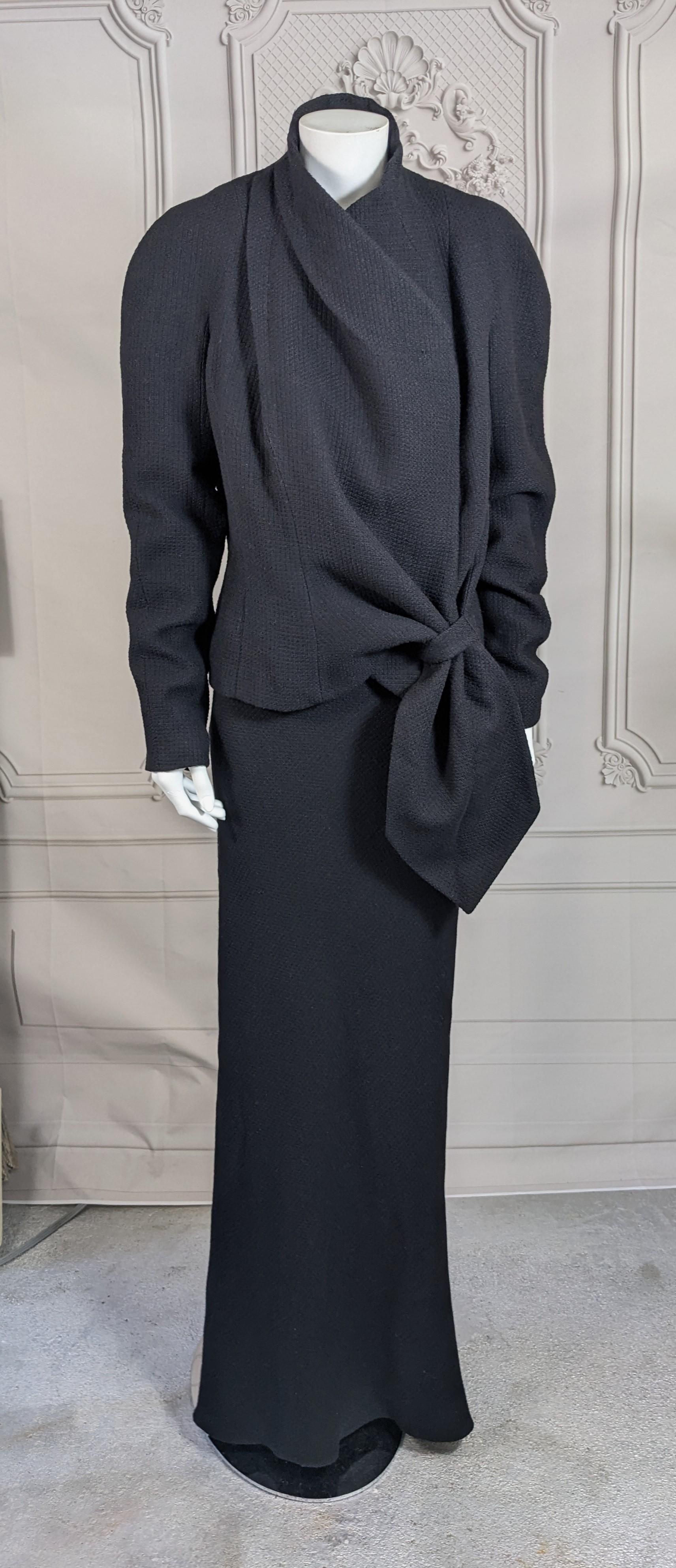Elegante esmoquin John Galliano de crepé de lana negro con textura, colección Maori Otoño-Invierno 1999. La chaqueta de corte asimétrico se envuelve en un 