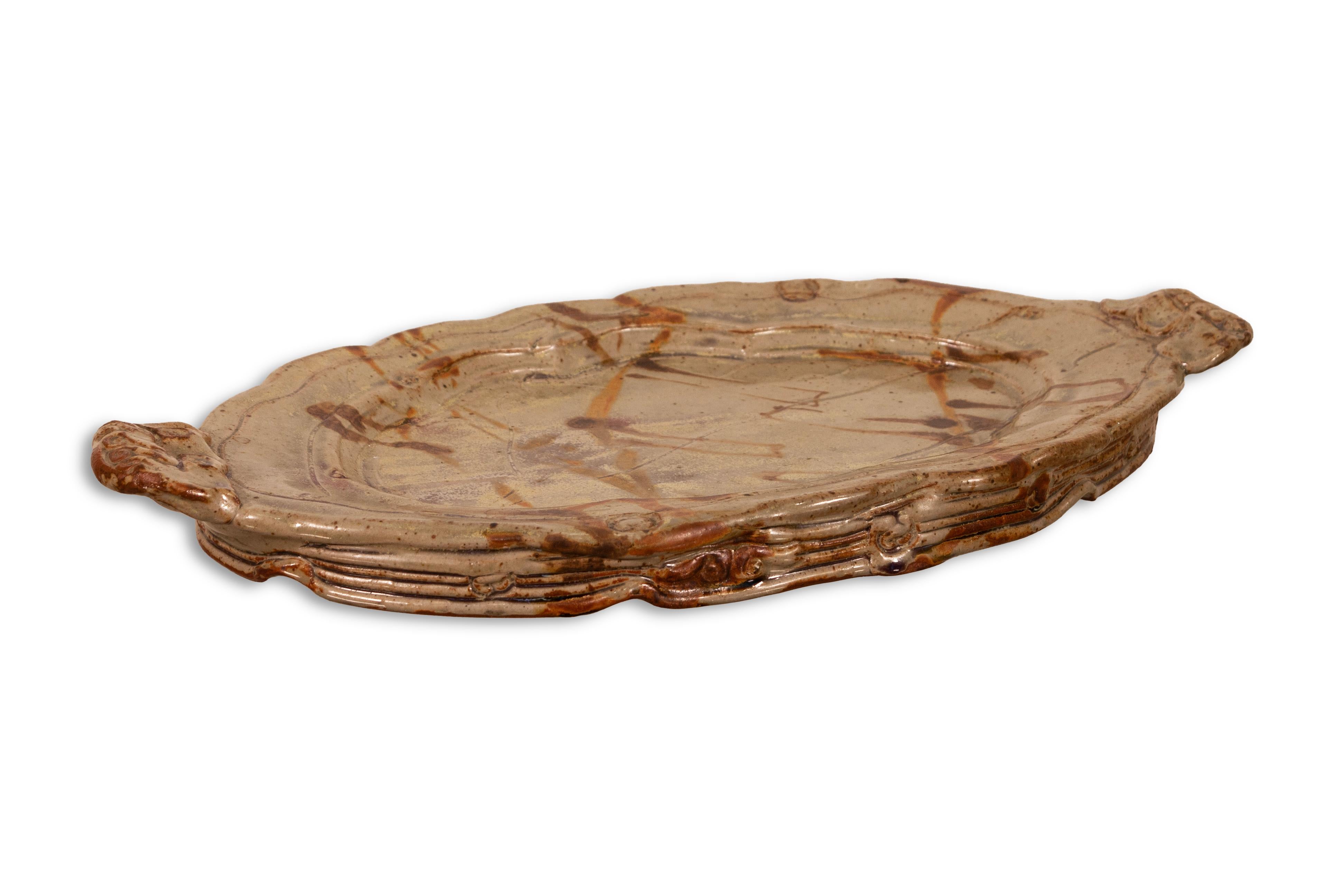 A modernist stoneware glazed ceramic platter by Detroit artist John Glick of Plum Tree Pottery. Circa late 20th century. Glazed in earthtones. Artisisnal yet functional and makes a unique modern statement. From a private collection.  In very good