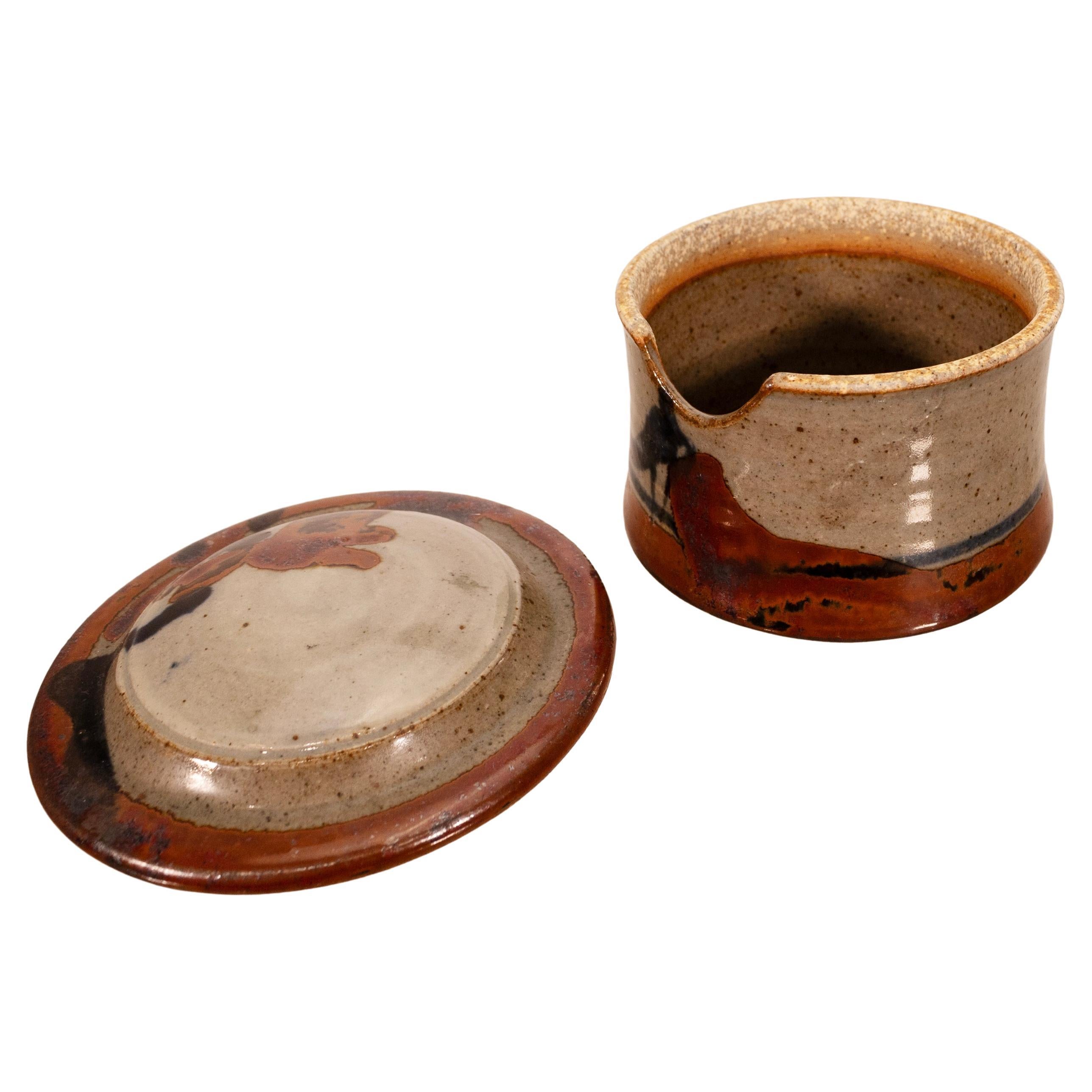 A modernist stoneware glazed ceramic sugar and creamer dish by Detroit artist John Glick of Plum Tree Pottery. Circa late 20th century. Glazed in earthtones. Artisisnal yet functional and makes a unique modern statement. From a private collection.