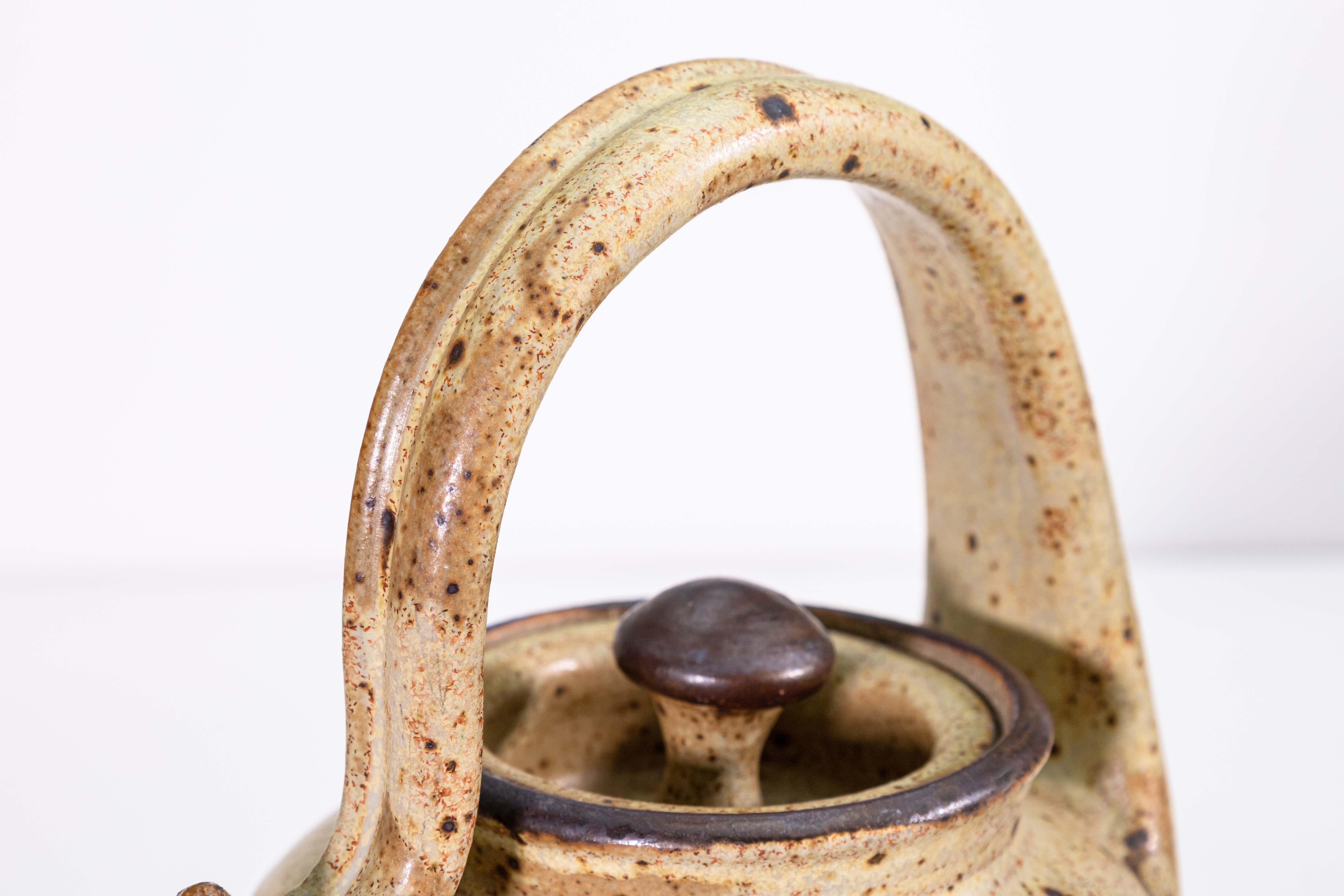 A modernist stoneware glazed ceramic tea pot by Detroit artist John Glick of Plum Tree Pottery. Circa late 20th century. Glazed in earthtones. Artisisnal yet functional and makes a unique modern statement. From a private collection. Dimensions: