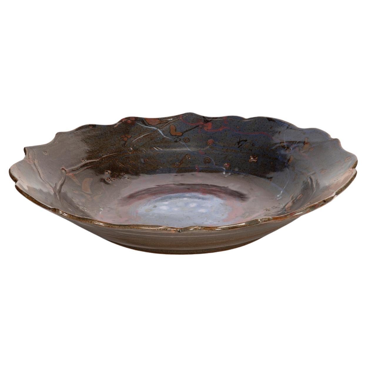The ceramic charger with scalloped edge is an example of the kind of work by which John Glick became so famous. He was seduced by the effects of the reduction kiln, which decreased the levels of oxygen during firing, inducing the flame to pull