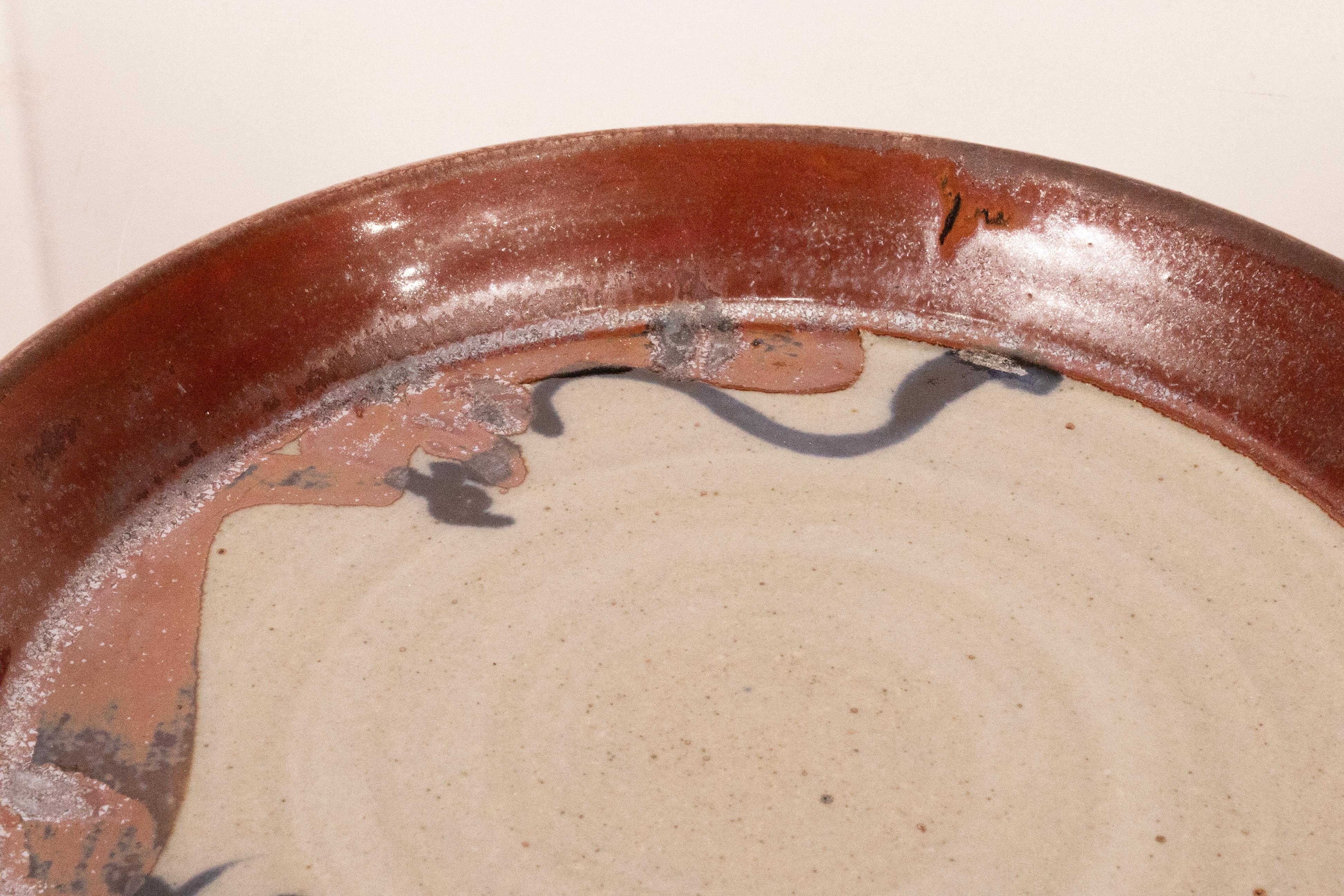 A modernist stoneware glazed ceramic set of 12 plates by Detroit artist John Glick of Plum Tree Pottery. Circa late 20th century. Glazed in earthtones. Artisisnal yet functional and makes a unique modern statement. From a private collection.  In