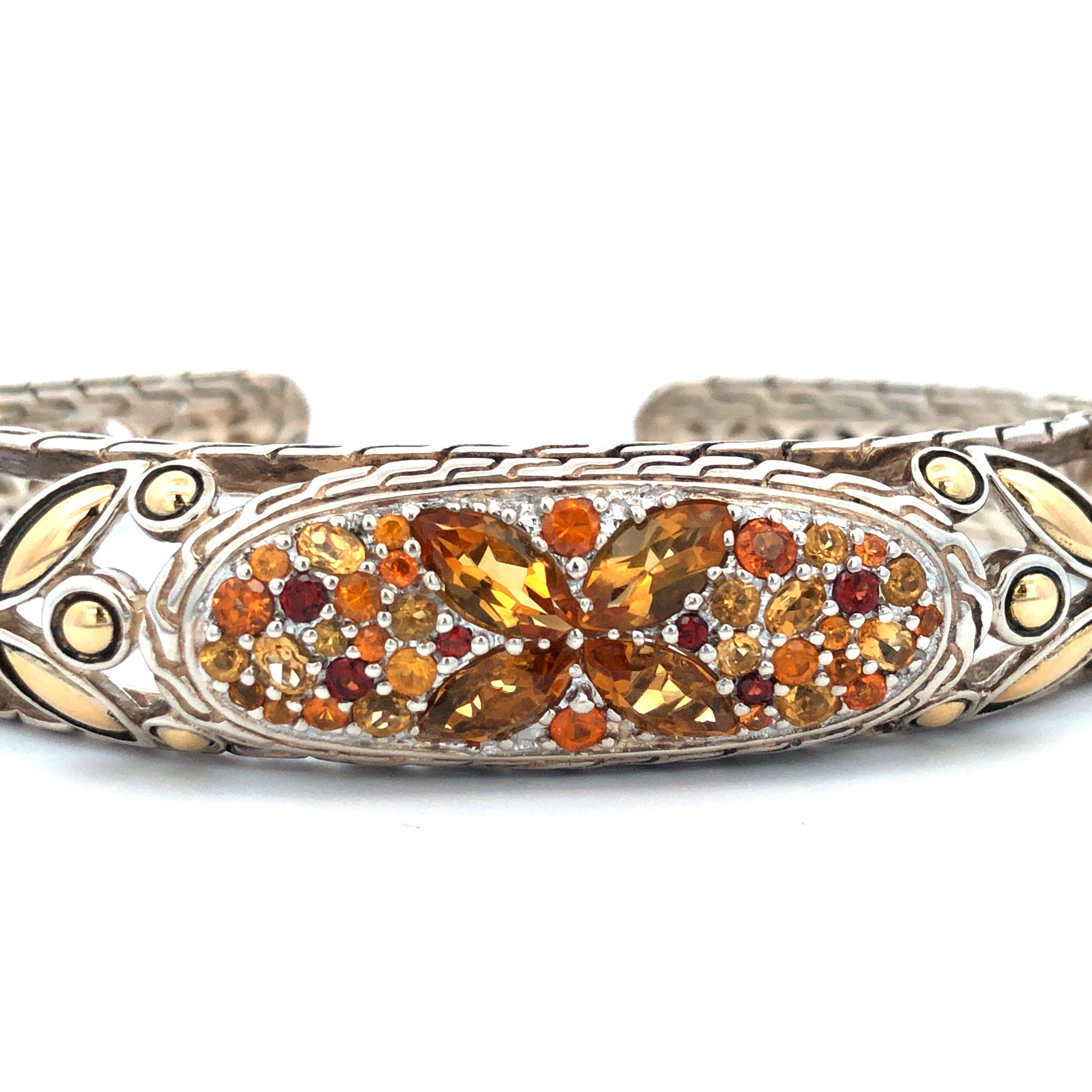 Crafted with meticulous artistry, this captivating cuff bracelet from John Hardy's Batu Kawung collection beautifully combines the cool allure of sterling silver with the warm radiance of 18k yellow gold and vibrant orange tone gemstones.

The