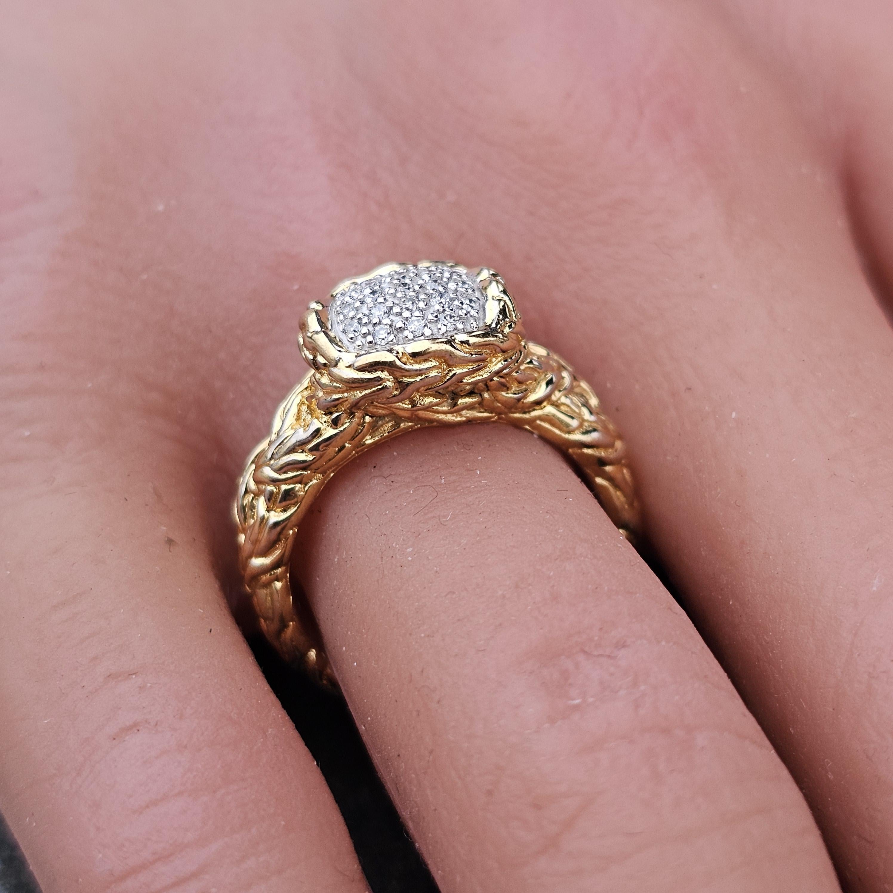 This John Hardy Classic Chain ring is a captivating piece of fine jewelry. Crafted from 18k yellow gold, it features a striking design with a dome shape. The ring is adorned with round white diamonds, adding a touch of elegance and sparkle. It is