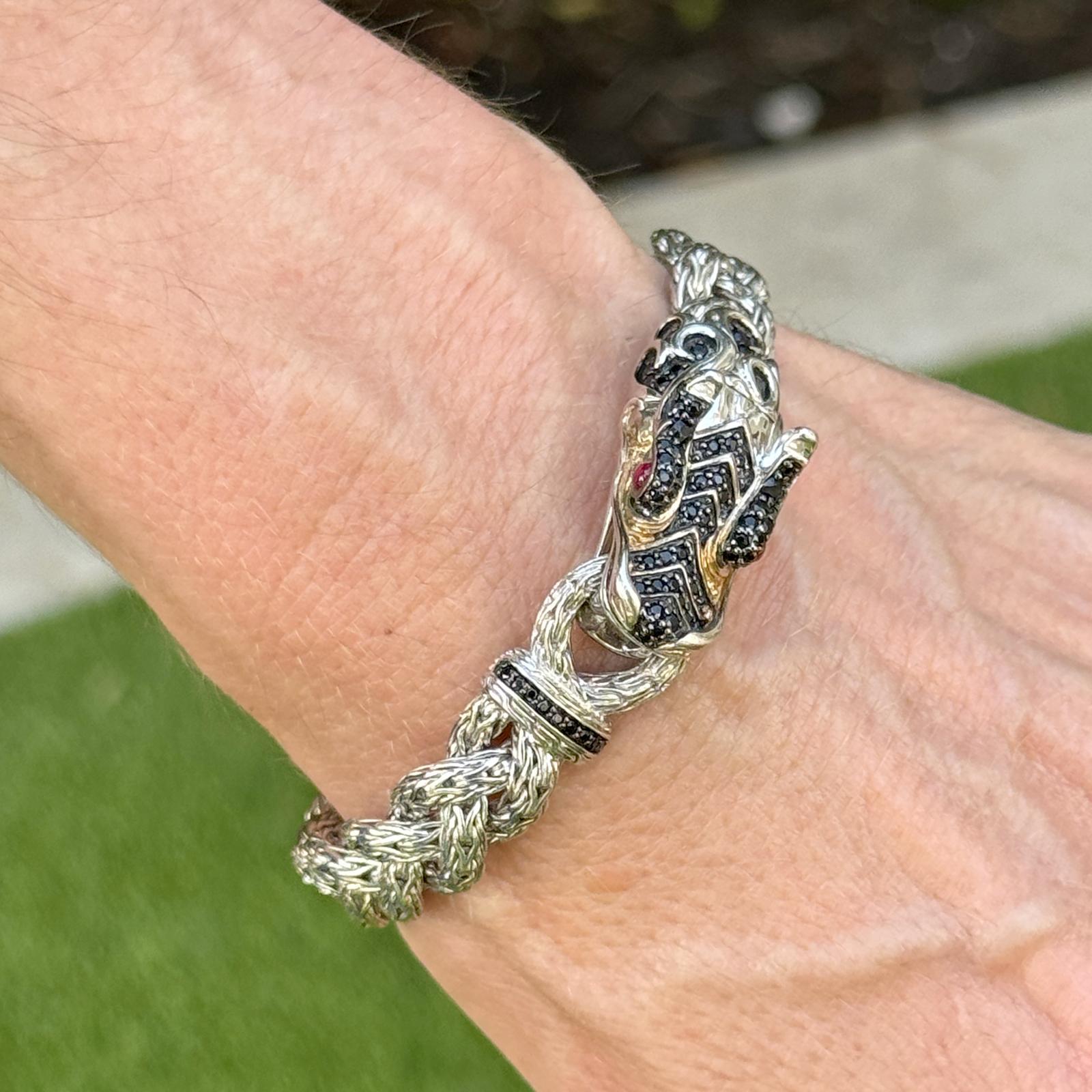 This striking Sterling Silver and 18K Yellow Gold John Hardy Dragon Bracelet features an intricately crafted dragon head adorned with fiery ruby eyes and black sapphire accents, symbolizing strength and protection. The bracelet measures 7 inches in