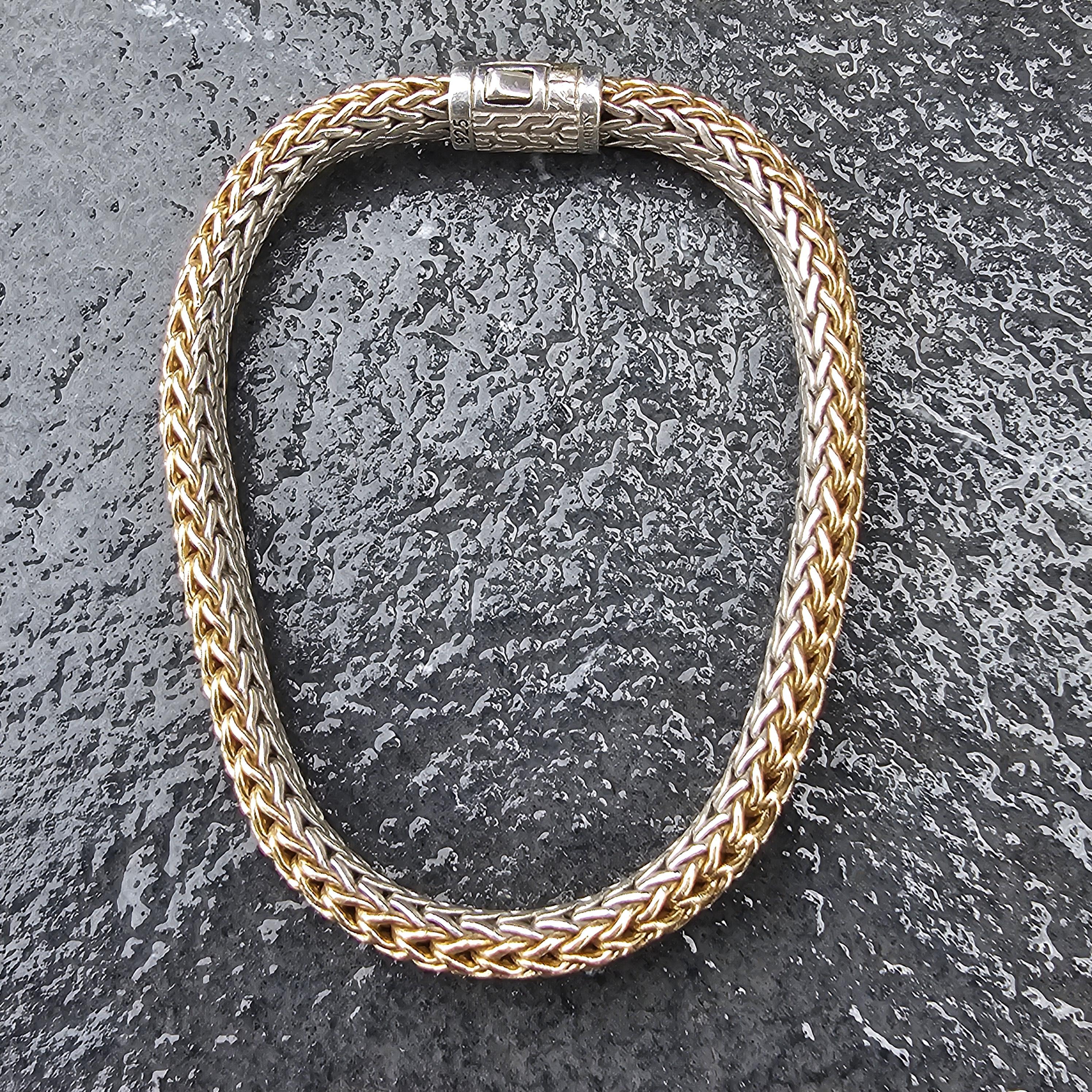 Questo sofisticato bracciale reversibile Icone di John Hardy è un'aggiunta straordinaria a qualsiasi collezione di gioielli. Realizzato in oro 18 carati e argento sterling, presenta un intricato disegno intrecciato che emana eleganza. Il bracciale