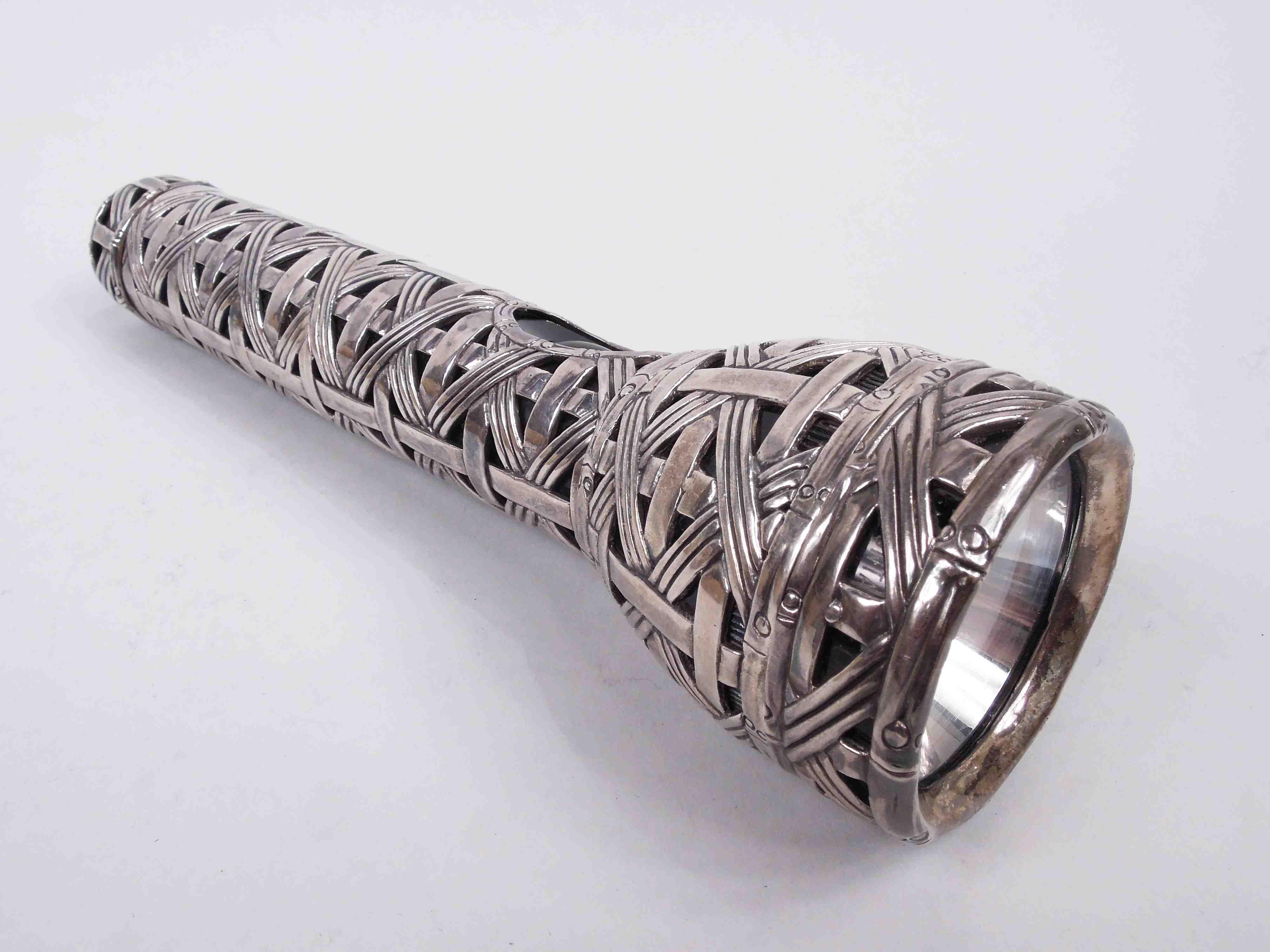 Jokey Y2K flashlight. Traditional flashlight encased in heavy silver weave. At end is applied medallion with the year 2000 encircled by the phrase “Light Your Way into the New Millennium”. An allusion to the infrastructure uncertainties when the