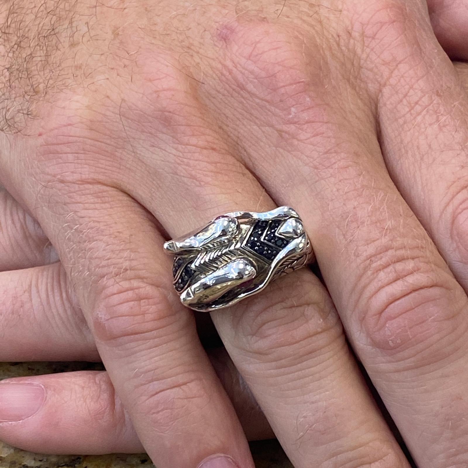 John Hardy Legends of Naga Dragon ring fashioned in sterling silver. The dragon ring features ruby eyes and black sapphire accents. The ring is currently size 9 (can be sized), and measures 15mm in width. Signed JH 925. 