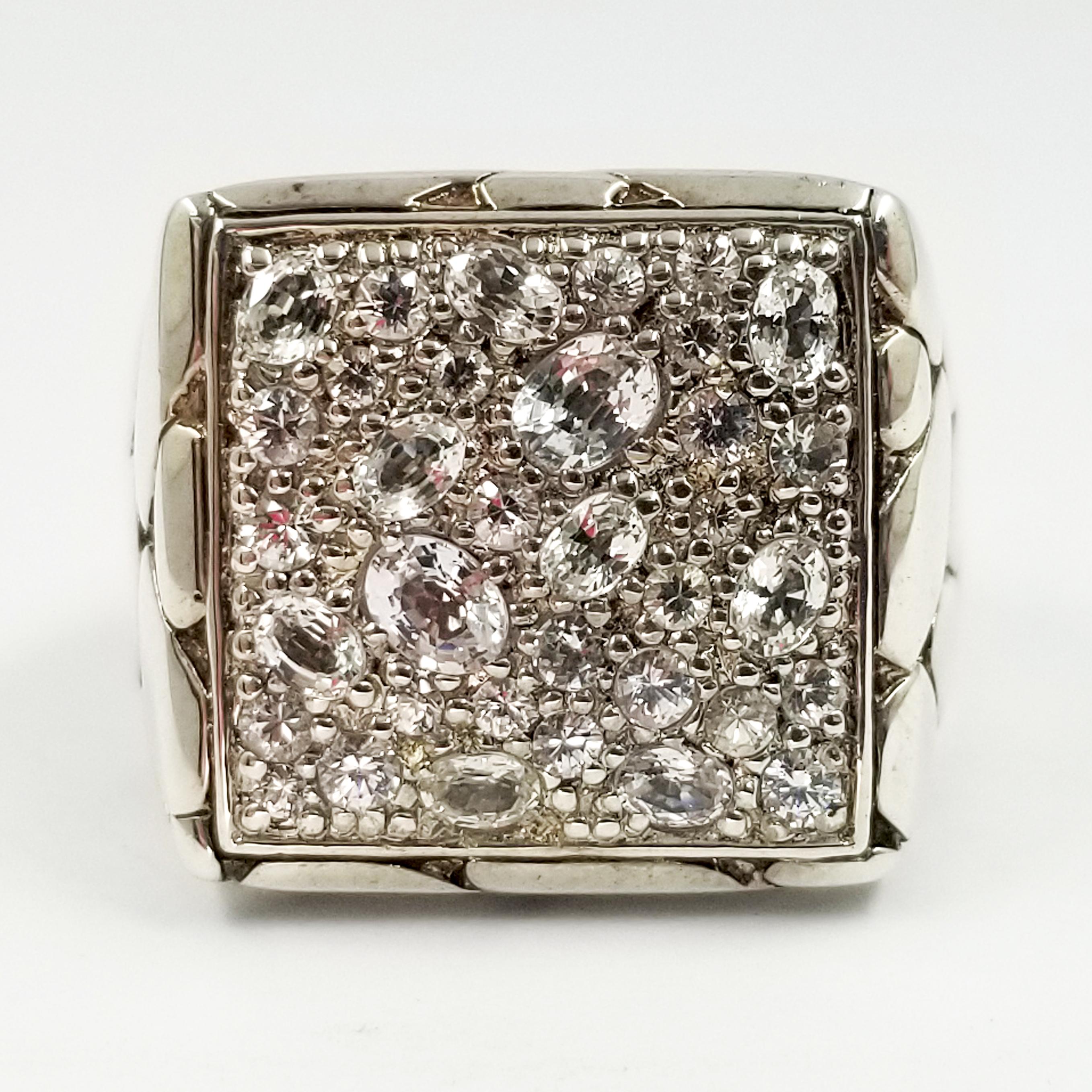 This sterling silver ring is hand assembled in Bali by the craftsmen at John Hardy. It is from the men's Kali jewelry collection, and features multiple prong-set faceted white sapphires on the top. The interior gallery is designed with a dragon