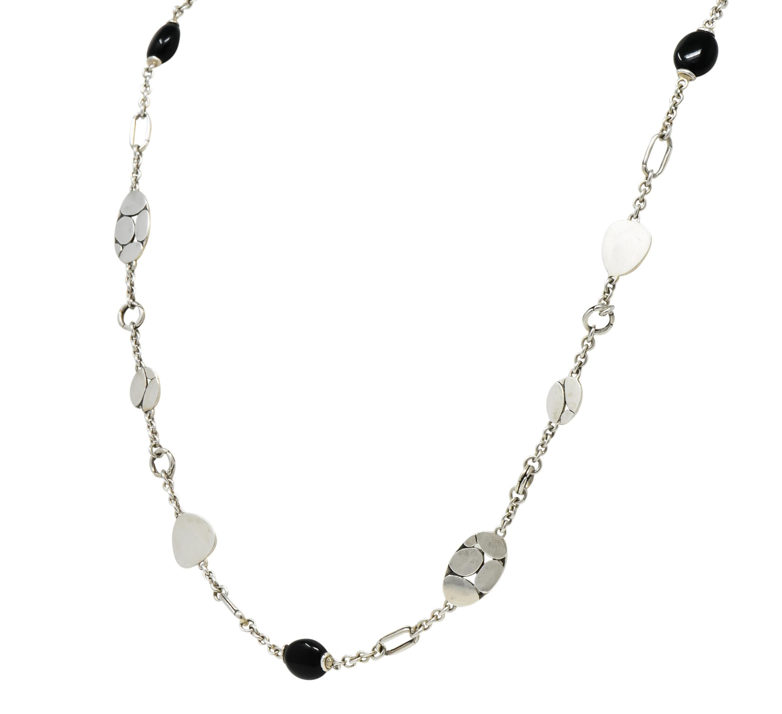 Station style necklace with seven smooth, oval onyx beads measuring approximately 8.0 mm x 9.0 mm, opaque, polished, and black

With flat sterling silver stations varying in size and shape, some polished bright, others with pierced dot