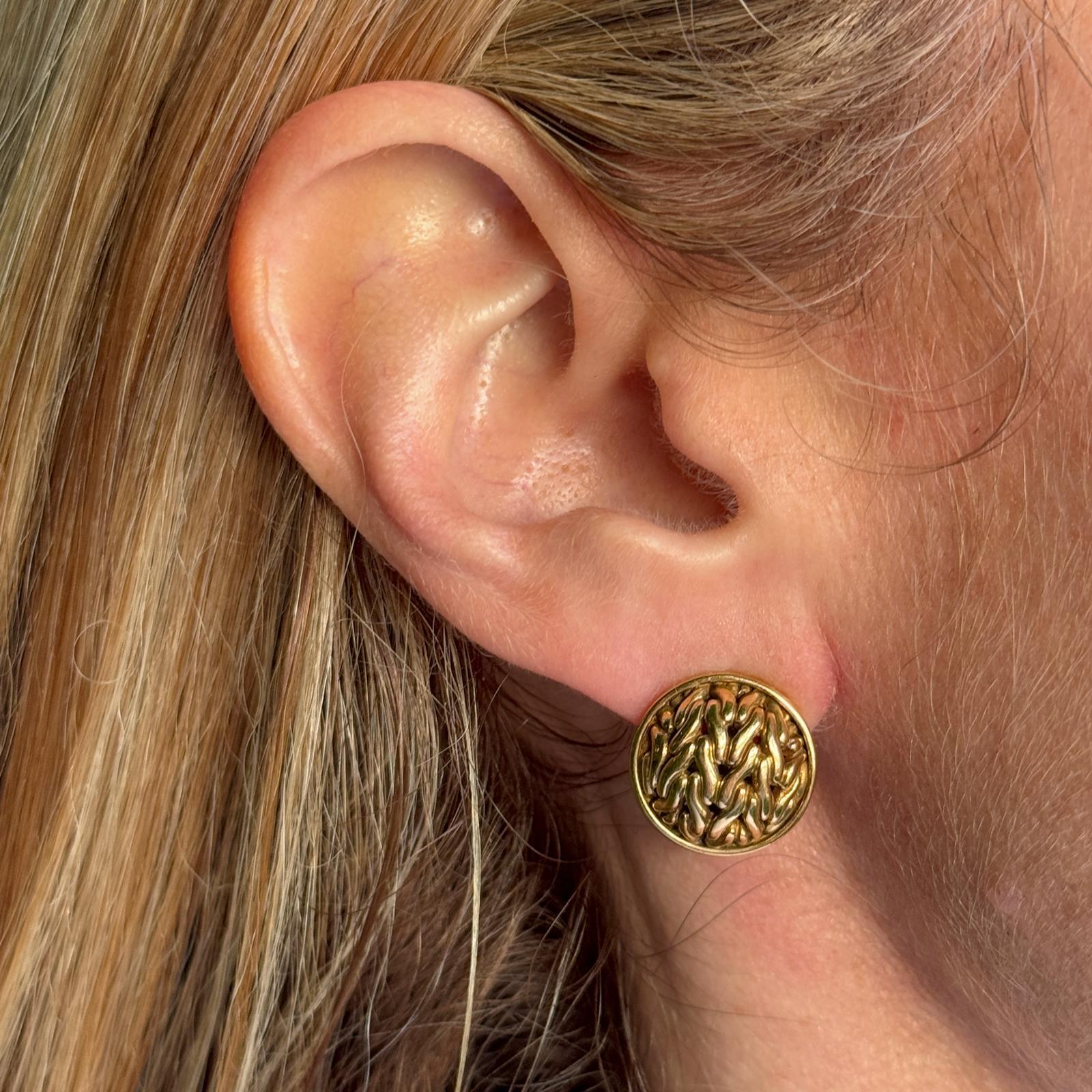 John Hardy button earrings crafted in 18 karat textured yellow gold. The earrings measure 15mm in diameter and feature lever-backs. Signed JH 18K. Weight: 10.3 grams.