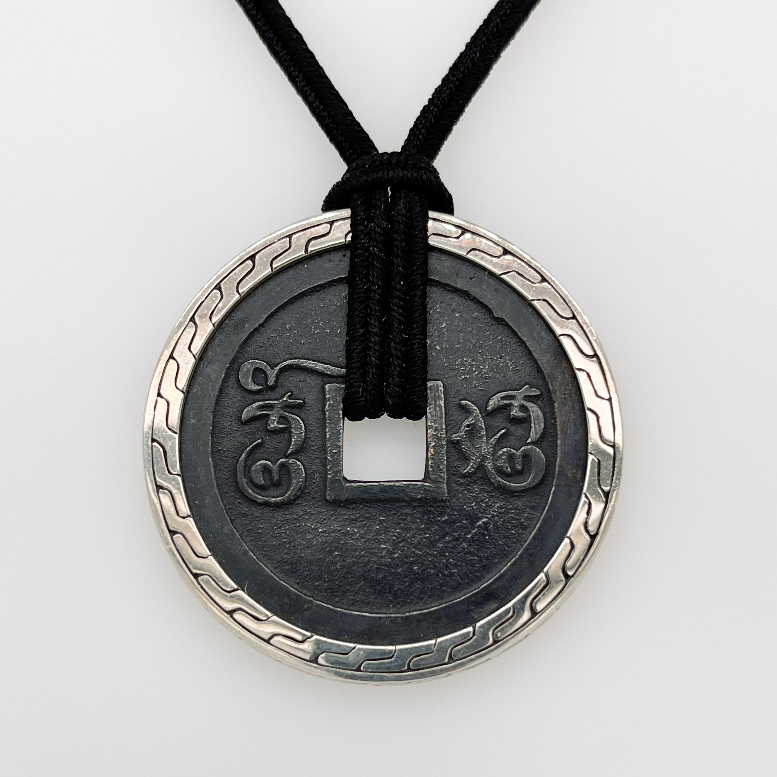 A fine ancient coin amulet or necklace.

By John Hardy.

With an iron (or bronze) amulet or coin that is bezel set in sterling silver.

The piece has Arabic characters on either side. 

Simply a great necklace from John Hardy!

Date:
21st