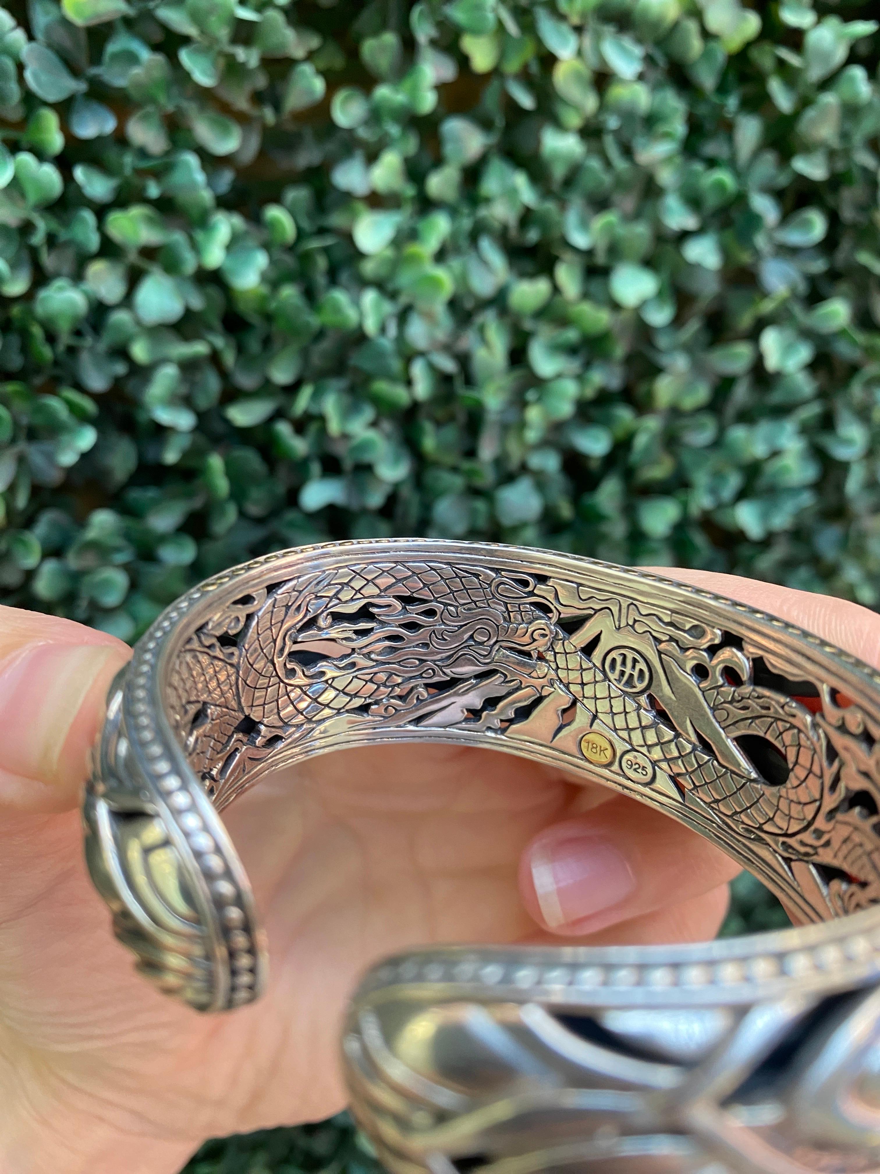 This cuff from John Hardy is crafted in sterling silver and features 18 karat yellow gold accents in a scale like pattern. The interior design features a detailed engraving of a dragon. Hinge clasp. 
Measurements: Width approximately 1