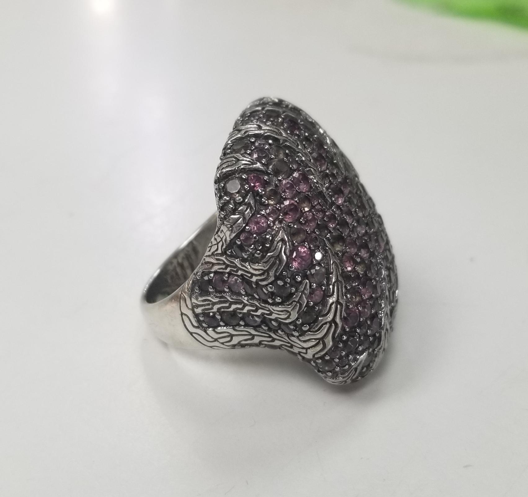 This sterling silver ring is hand assembled in Bali by the craftsmen at John Hardy. It is from the men's Kali jewelry collection, and features multiple prong-set faceted pink sapphires on the top. The interior gallery is designed with a tiger motif,