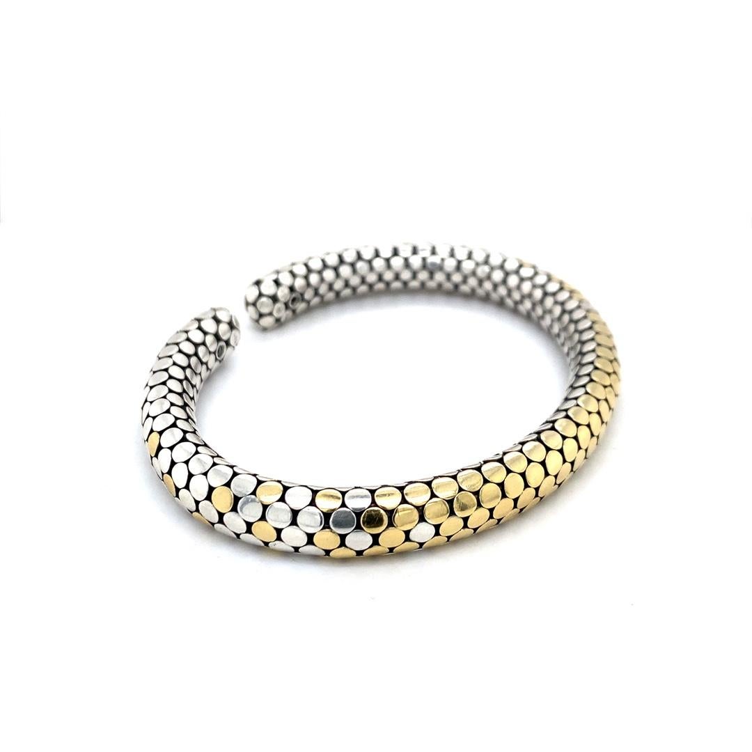 This stunning cuff bracelet designed by John Hardy features a dot pattern made of 18 karat gold accents on a sterling silver base. The bracelet measures 8.75mm wide and can fit up to a 7