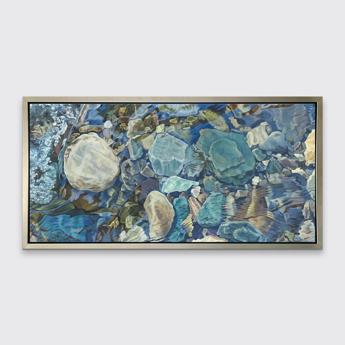 This limited edition print by John Harris captures a close up view of river rocks beneath lightly-rippling water in a horizontal format. It features a cool blue and earth-toned palette, with natural light reflecting lightly off the moving water.