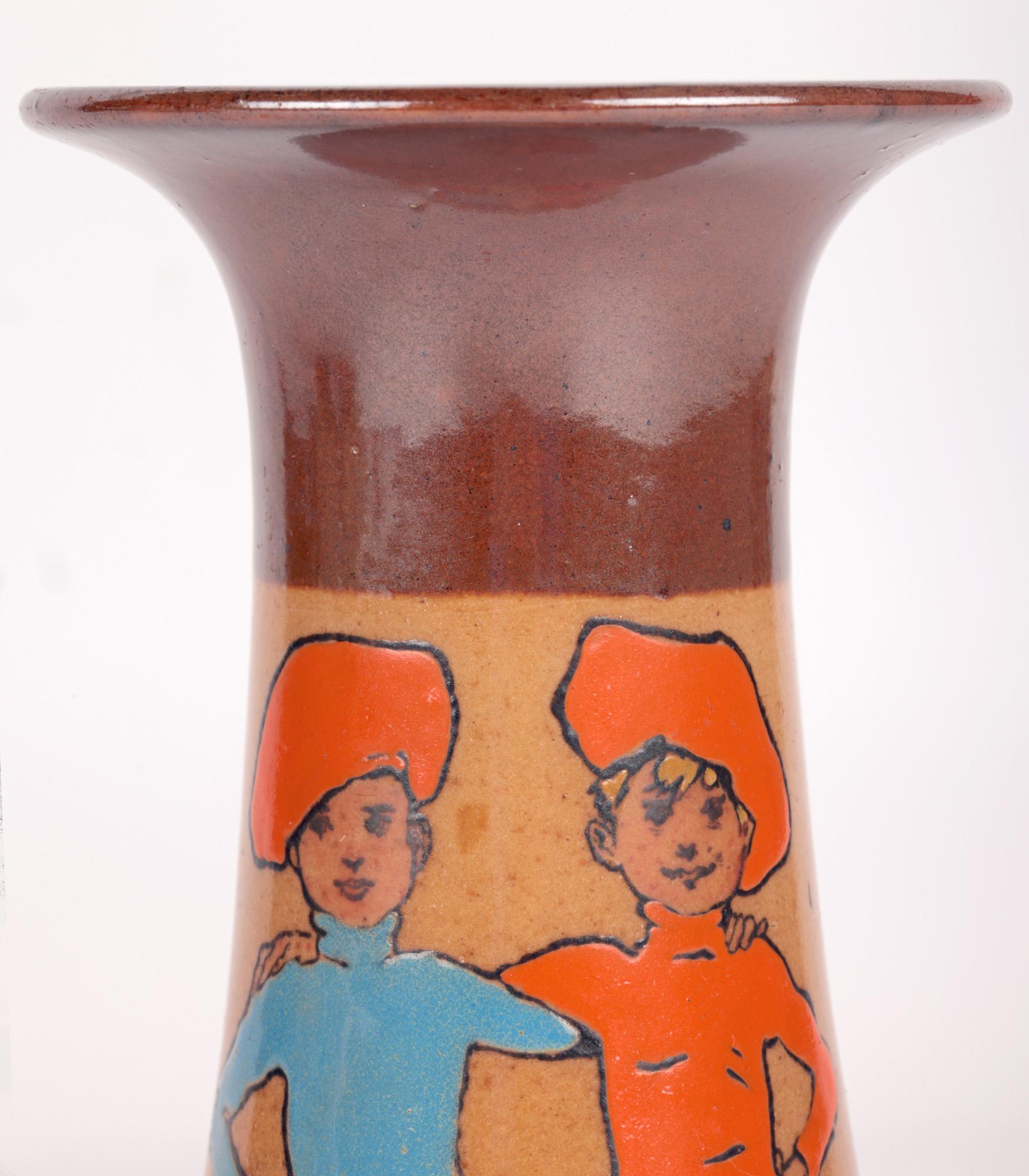 Un vase Doulton Lambeth Twins Ware très recherché, peint avec des jumeaux par le célèbre artiste et illustrateur John Hassall (britannique, 1868-1948) et datant d'environ 1905. Le vase en grès repose sur un pied en forme d'anneau, avec un corps