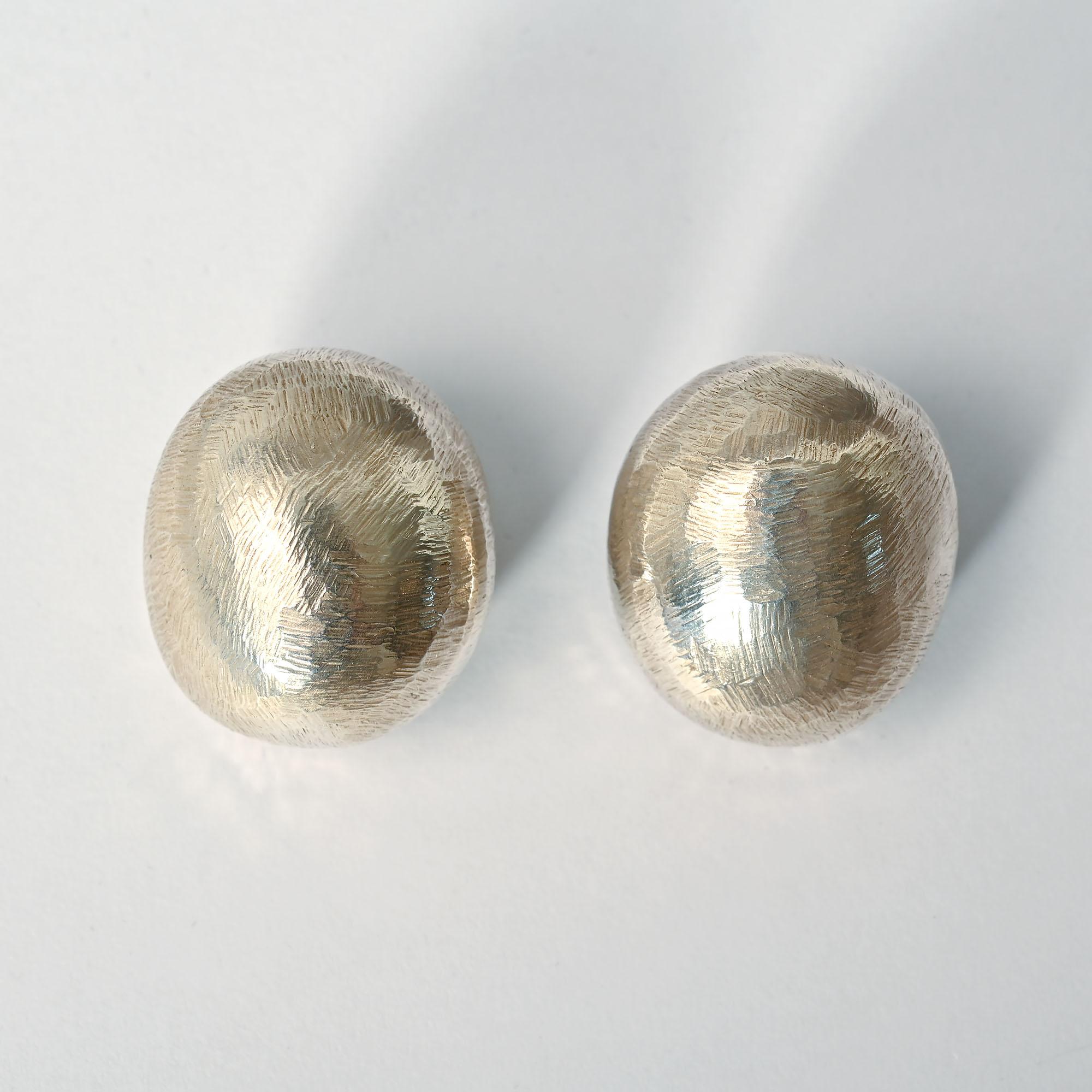 Boucles d'oreilles ovales en argent sterling de John Iversen de sa série Pebble. Elles ont la surface légèrement rayée qu'il privilégie souvent. Les boucles d'oreilles mesurent 7/8