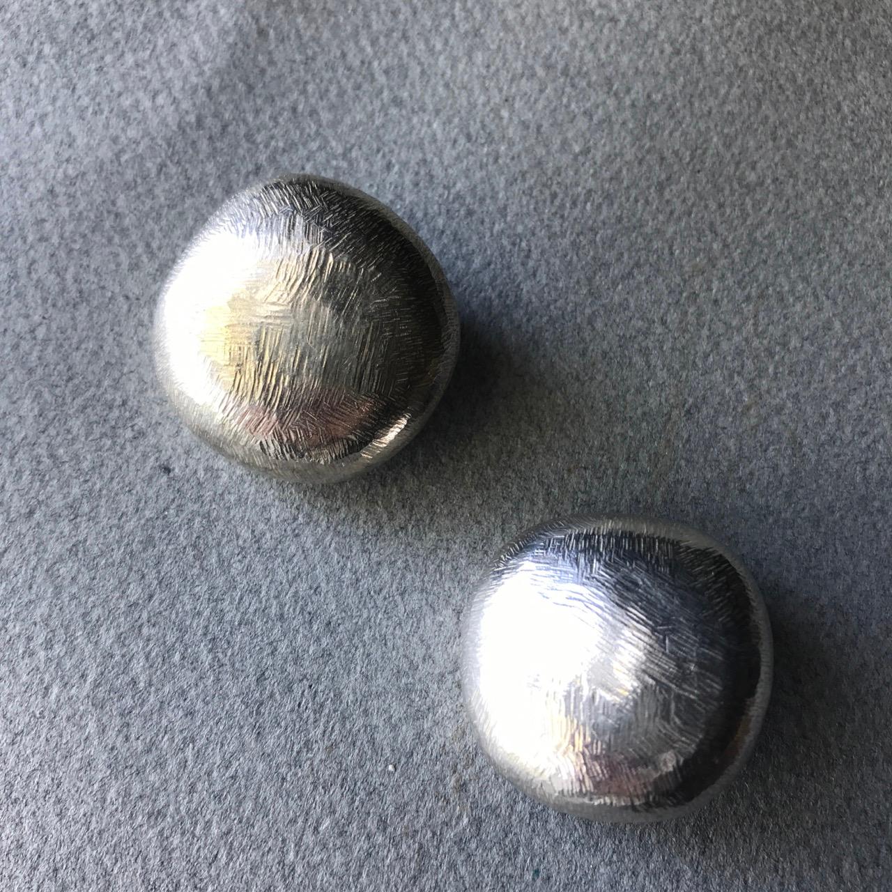John Iversen Sterling Silver Pebble Earrings. 
Echoing the natural shape of a pebble, these Sterling Silver earrings have a slightly textured and brushed surface with a clip-on back. These earrings are large in scale but very comfortable to