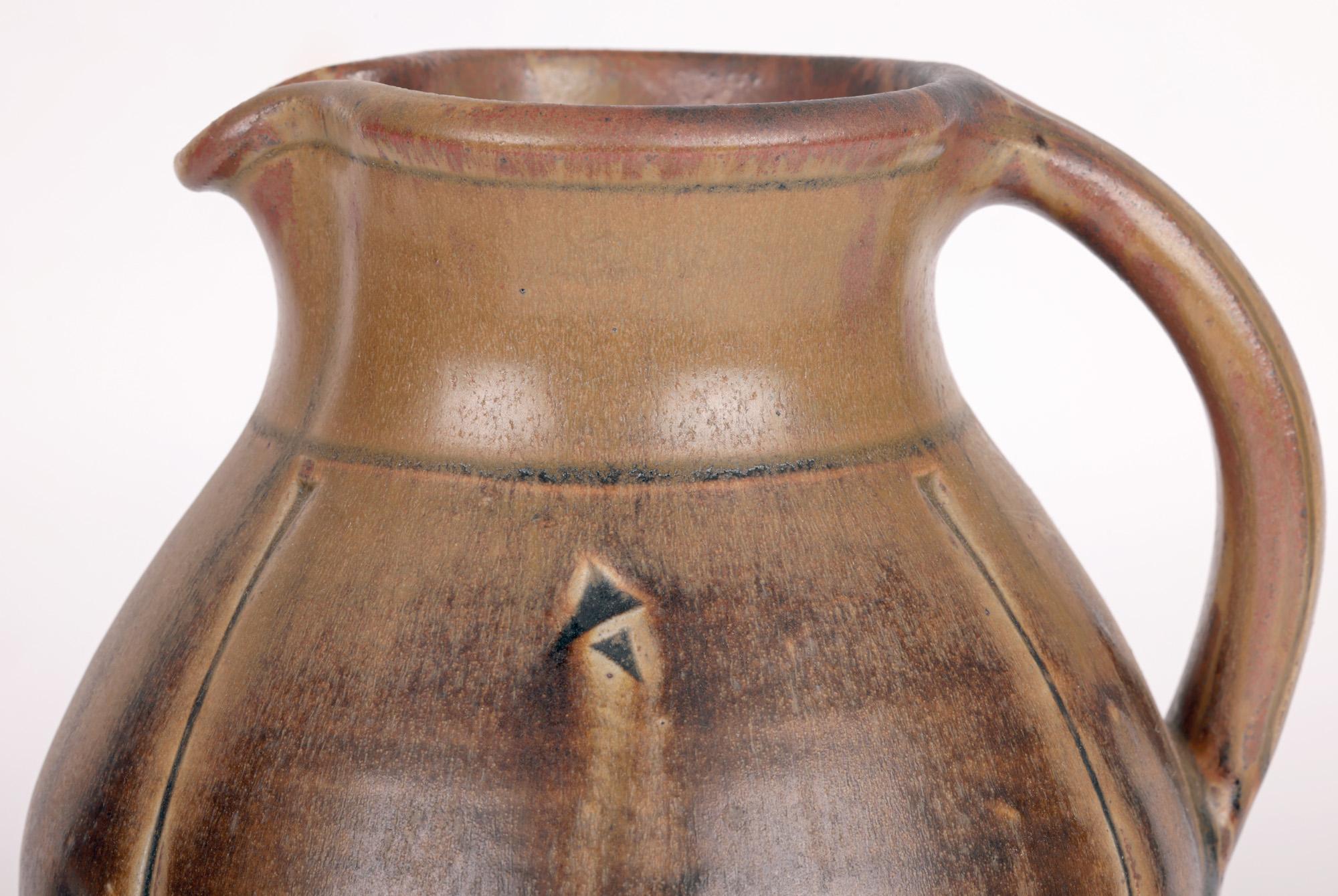 A large and stylish Cotswold Pottery studio pottery jug with incised patterning by renowned potter John Jelfs (British. b.1946) and dating from around 1997. The heavily made stoneware jug is of rounded bulbous shape standing on a flat round unglazed