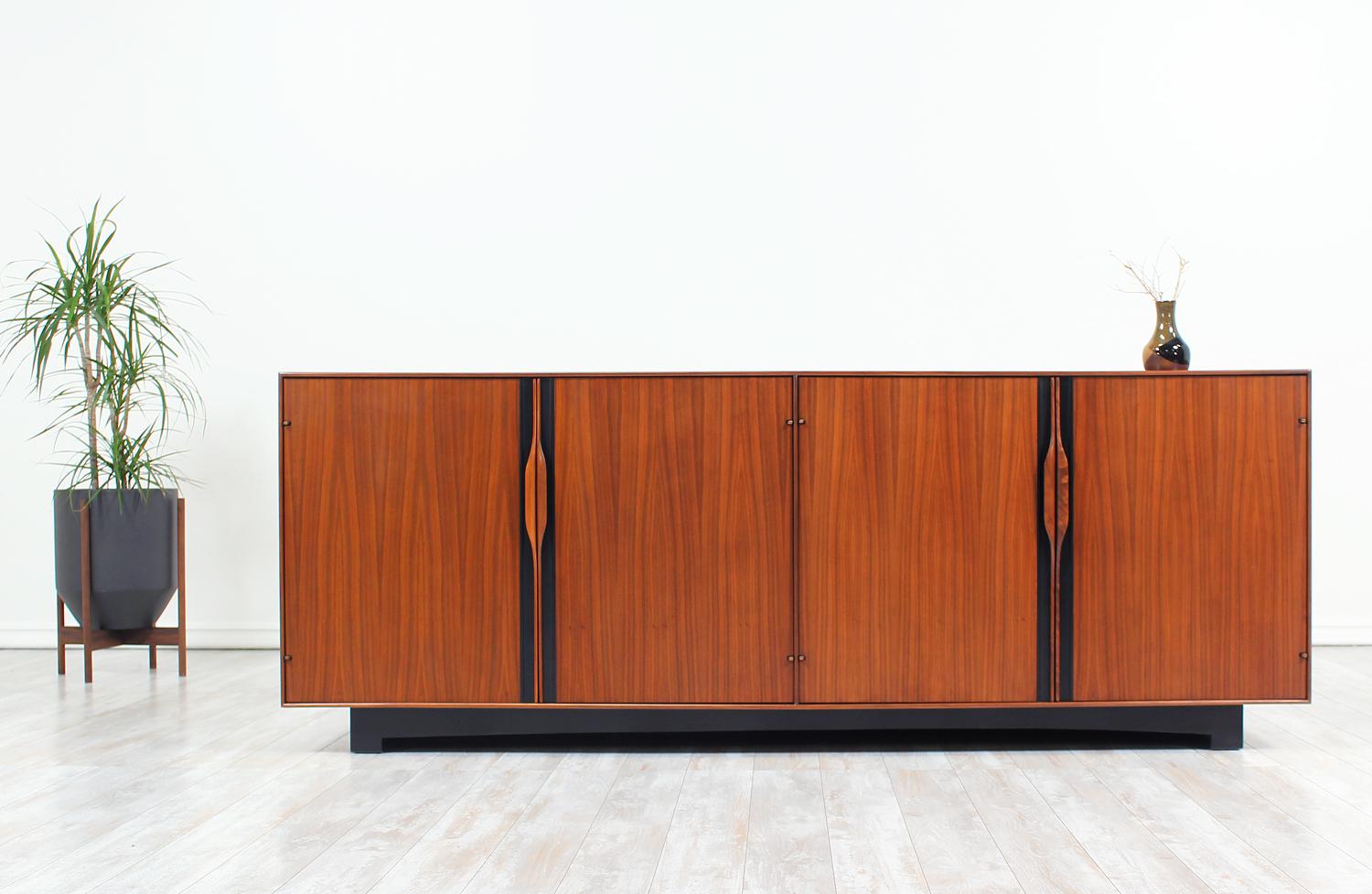 Mid-Century credenza designed by John Kapel for Glenn of California in the United States circa 1950’s. Beautifully crafted in walnut wood, this versatile credenza design features the designer’s signature sculpted walnut handles that open to reveal