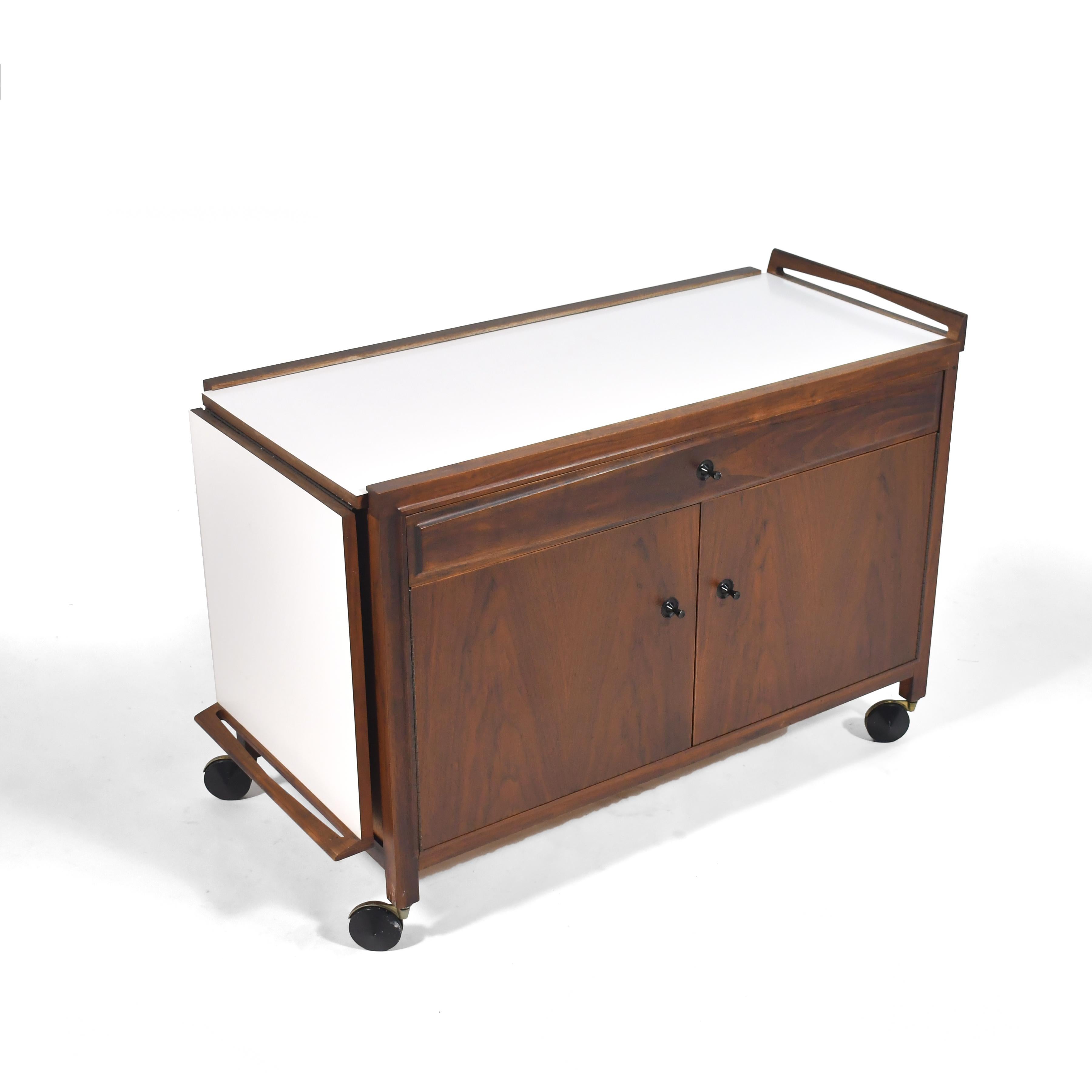 Ce magnifique et très fonctionnel design de John Kapel est composé d'un coffret en noyer avec un plateau expansé en mica blanc et des détails remarquables tels que la poignée sculptée et les tirettes coniques. Il comporte un tiroir peu profond